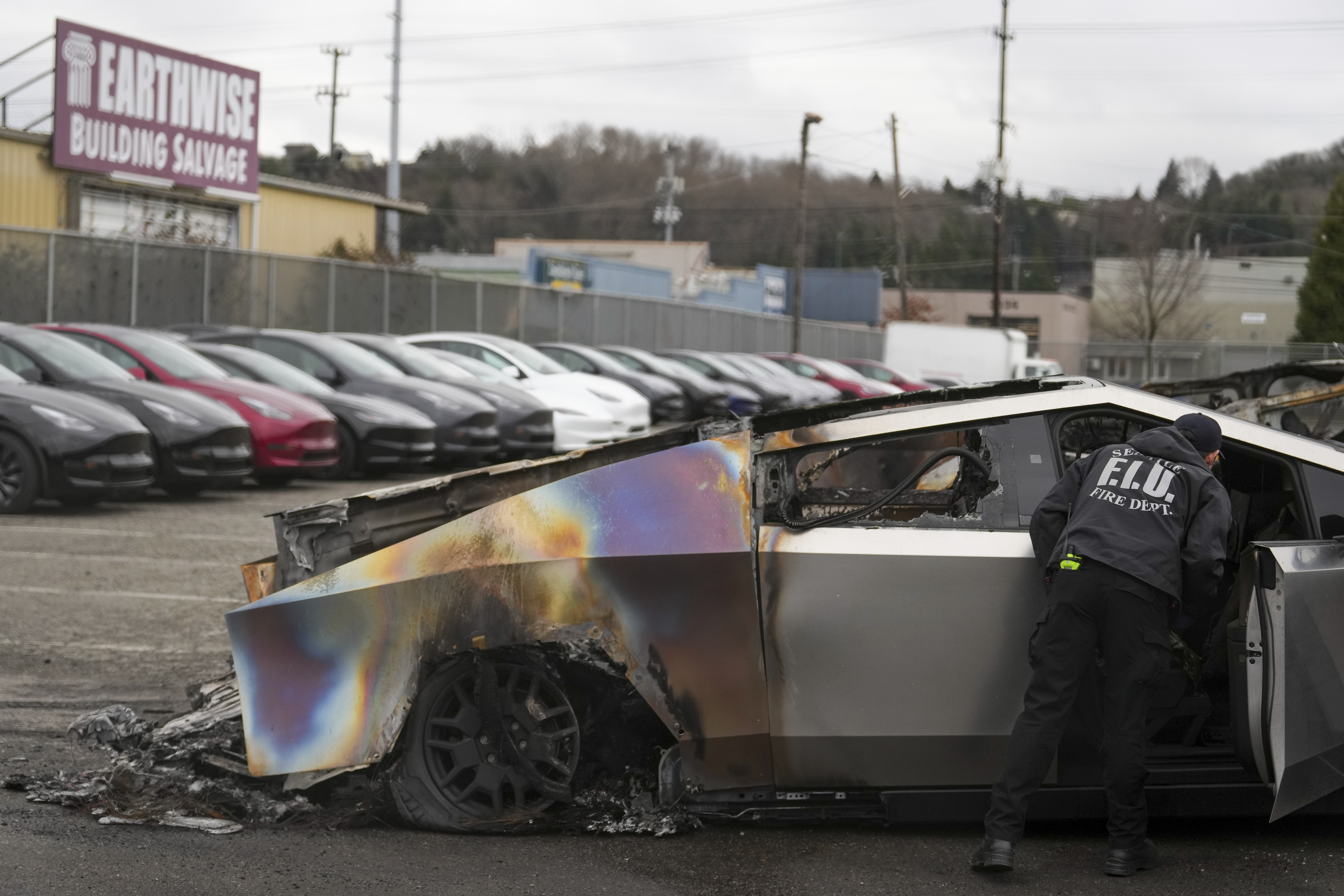 A member of the Seattle Fire Department inspects a burned Tesla Cybertruck at a Tesla lot in Seattle, Monday, March 10, 2025.<br />(Lindsey Wasson / AP Photo)