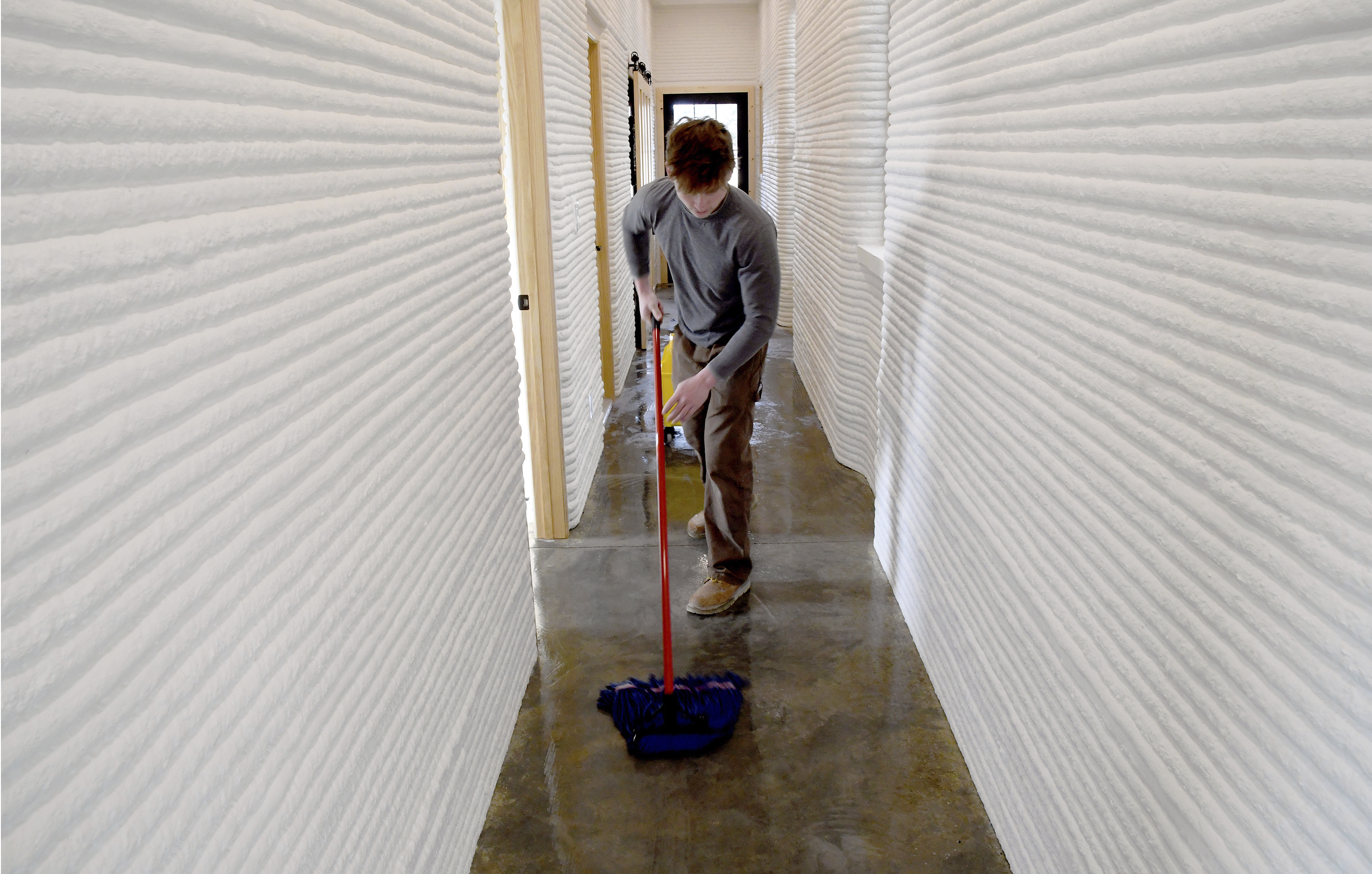 David Leach mops the floor of a 3D-printed concrete home built by VeroTouch in Buena Vista, Colo., on Feb. 19, 2025.<br />(Thomas Peipert / AP Photo)