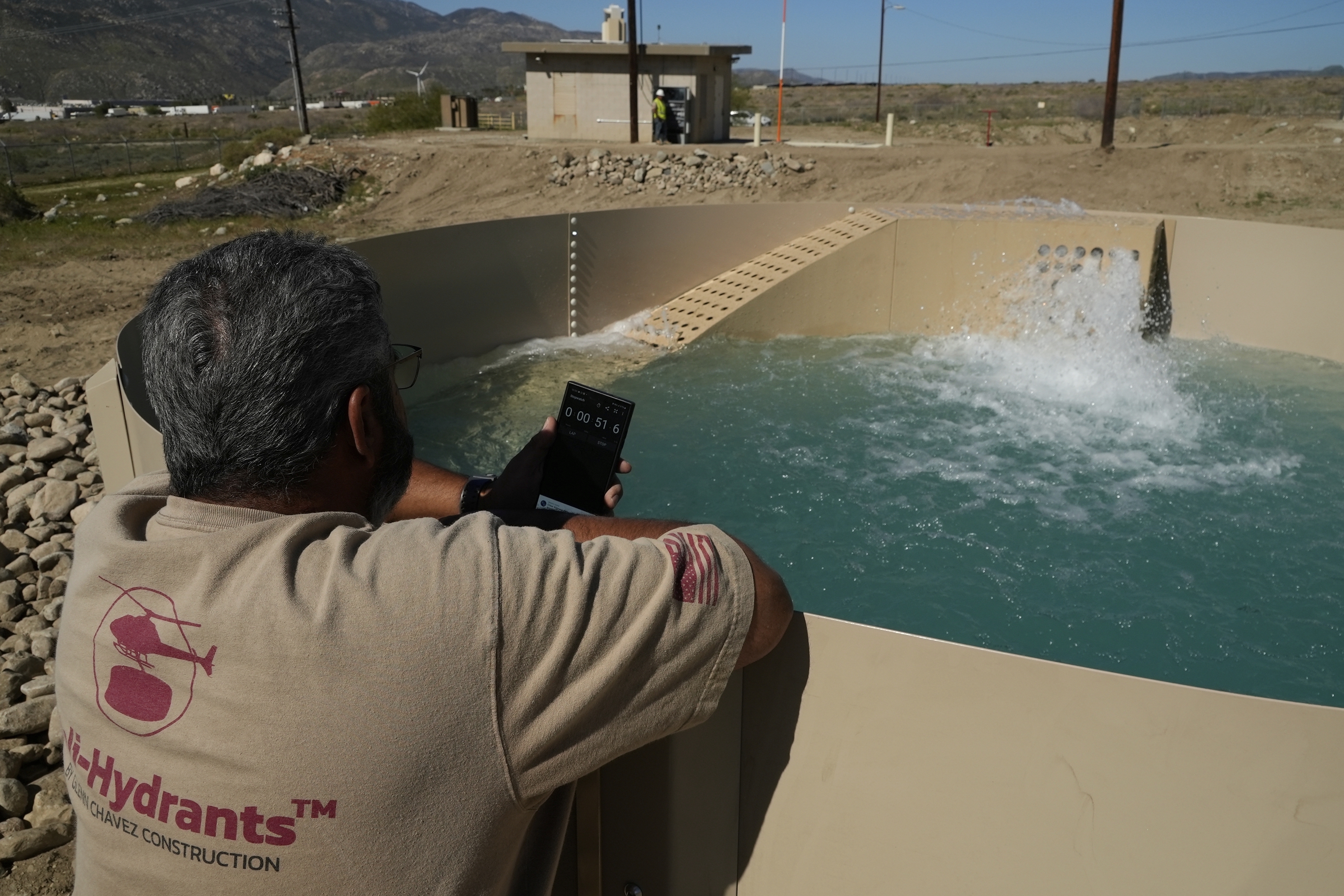 Glenn Chavez sets a timer as water fills a newly installed Heli-Hydrant, a small, open tank that helicopters can rely on to get water faster for urban fires, Friday, April 11, 2025, in Cabazon, Calif.<br />(Brittany Peterson / AP Photo)