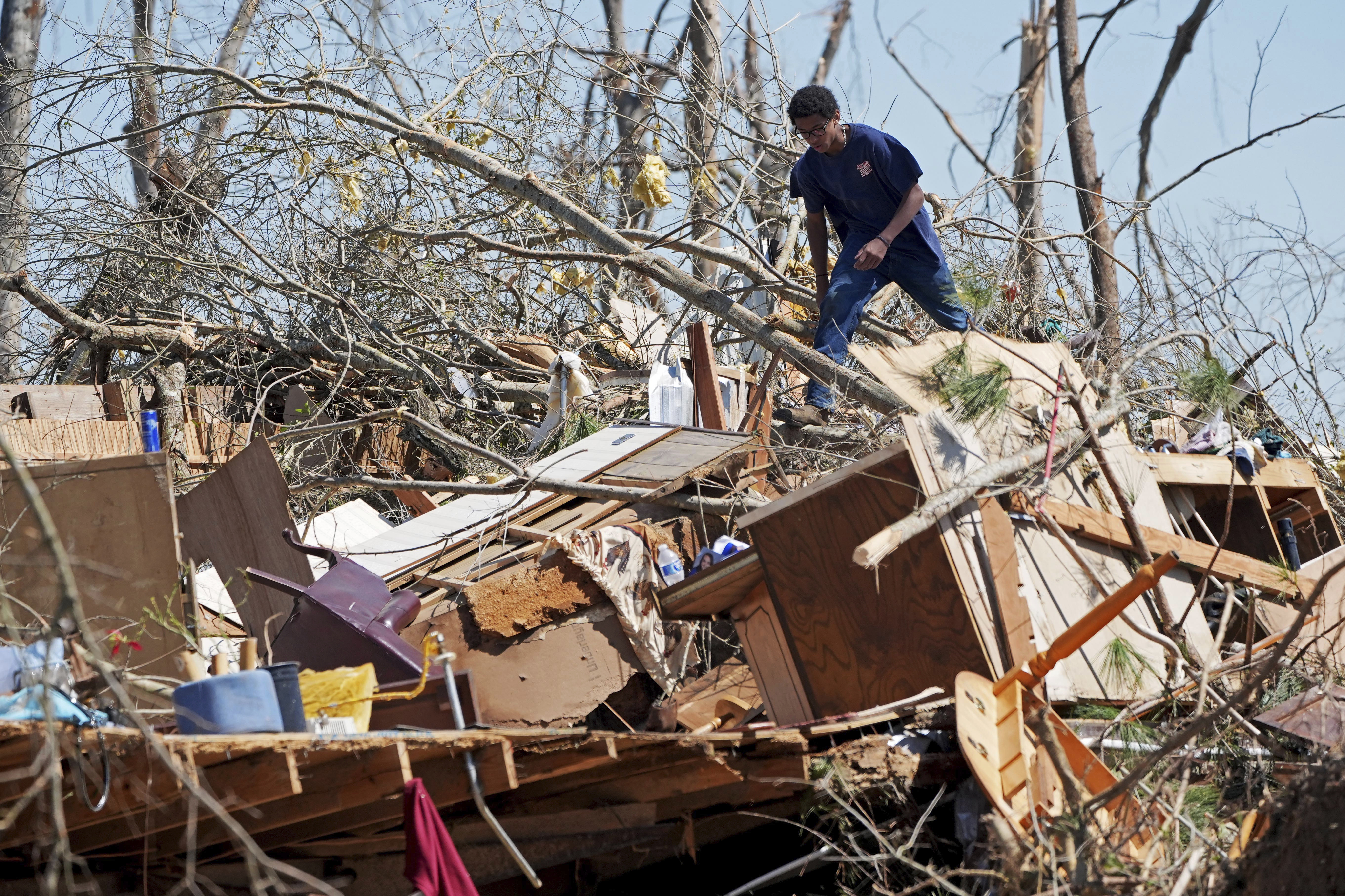 Family friend Trey Bridges, 16, climbs a mountain of tornado debris to help the Blansett family recover items not destroyed by Saturday&#039;s tornado, Sunday, March 16, 2025, in Tylertown, Miss.<br />(Rogelio V. Solis / AP Photo)