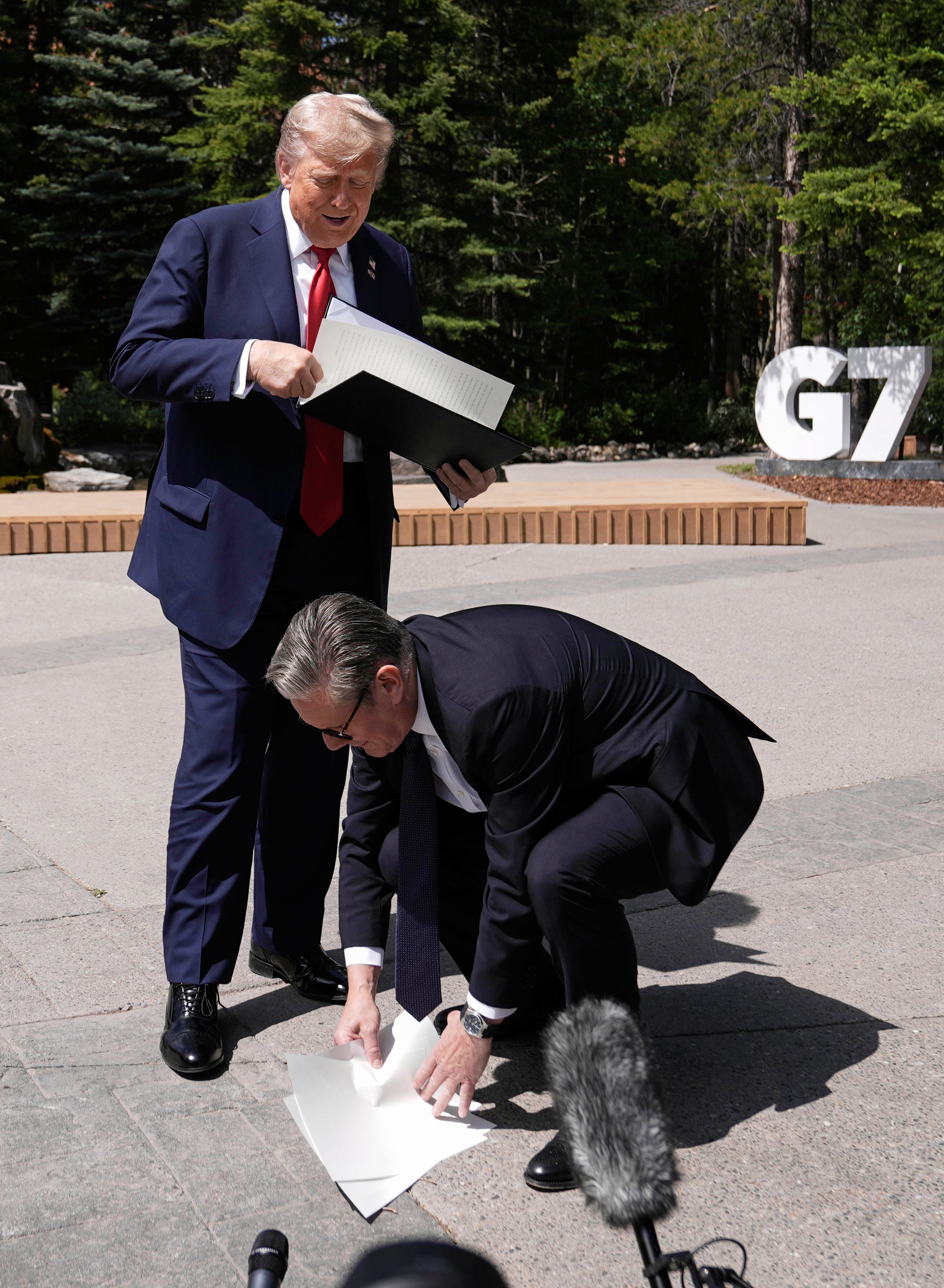 Britain&#039;s Prime Minister Keir Starmer picks up the U.K.-U.S. trade agreement papers dropped by U.S. President Donald Trump before speaking to the media at the G7 summit in Kananaskis, Alberta, Monday June 16, 2025.<br />(Stefan Rousseau / Pool Photo via AP)