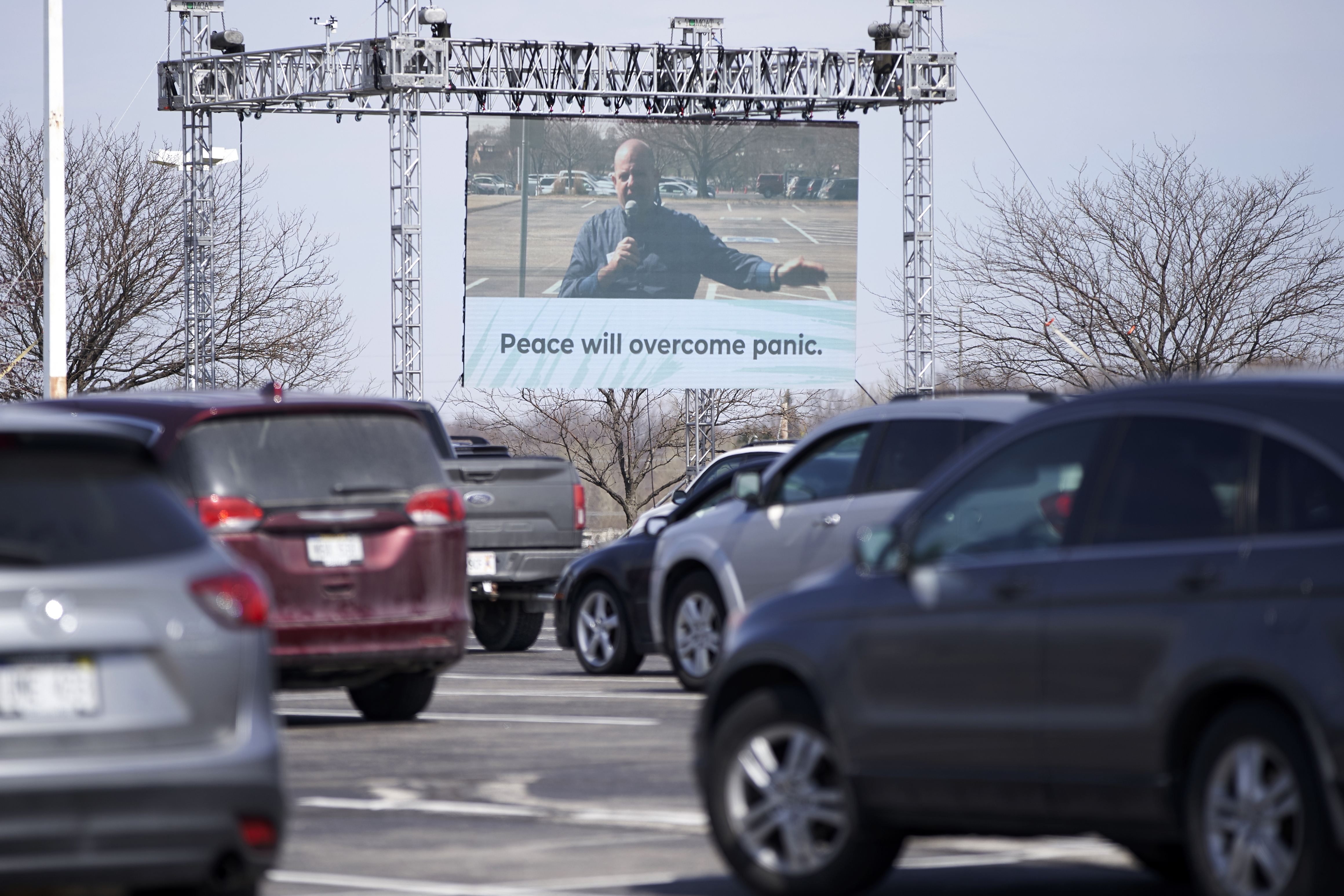 Rev. Greg Griffith, lead pastor at King of Kings church in Omaha, is seen on a giant screen during a drive-in Palm Sunday service, Sunday, April 5, 2020. Vehicles were parked to observe social distancing and worshippers were asked to stay in their cars and not roll down windows due to the coronavirus outbreak. (AP Photo/Nati Harnik)