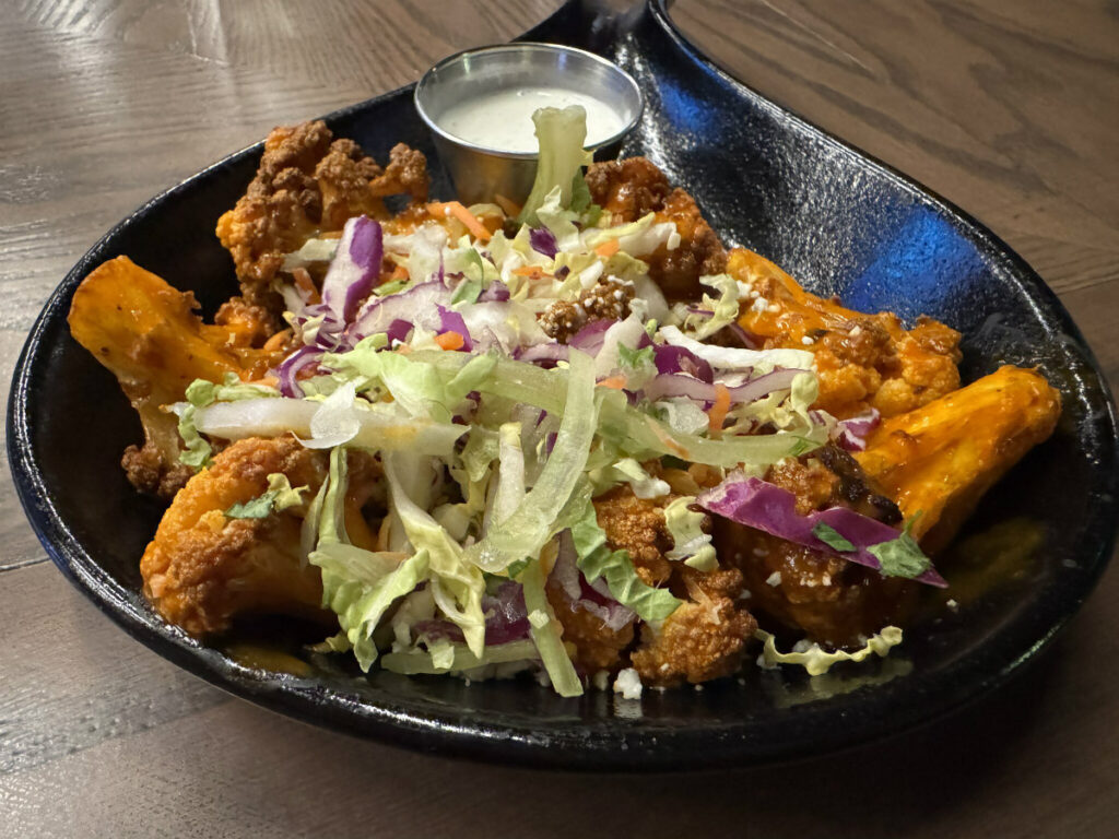 Cauliflower florets are bathed in a house-made Buffalo sauce and served with a celery slaw, blue cheese crumbles and ranch for dipping.<br />(Sarah Baker Hansen / Flatwater Free Press)