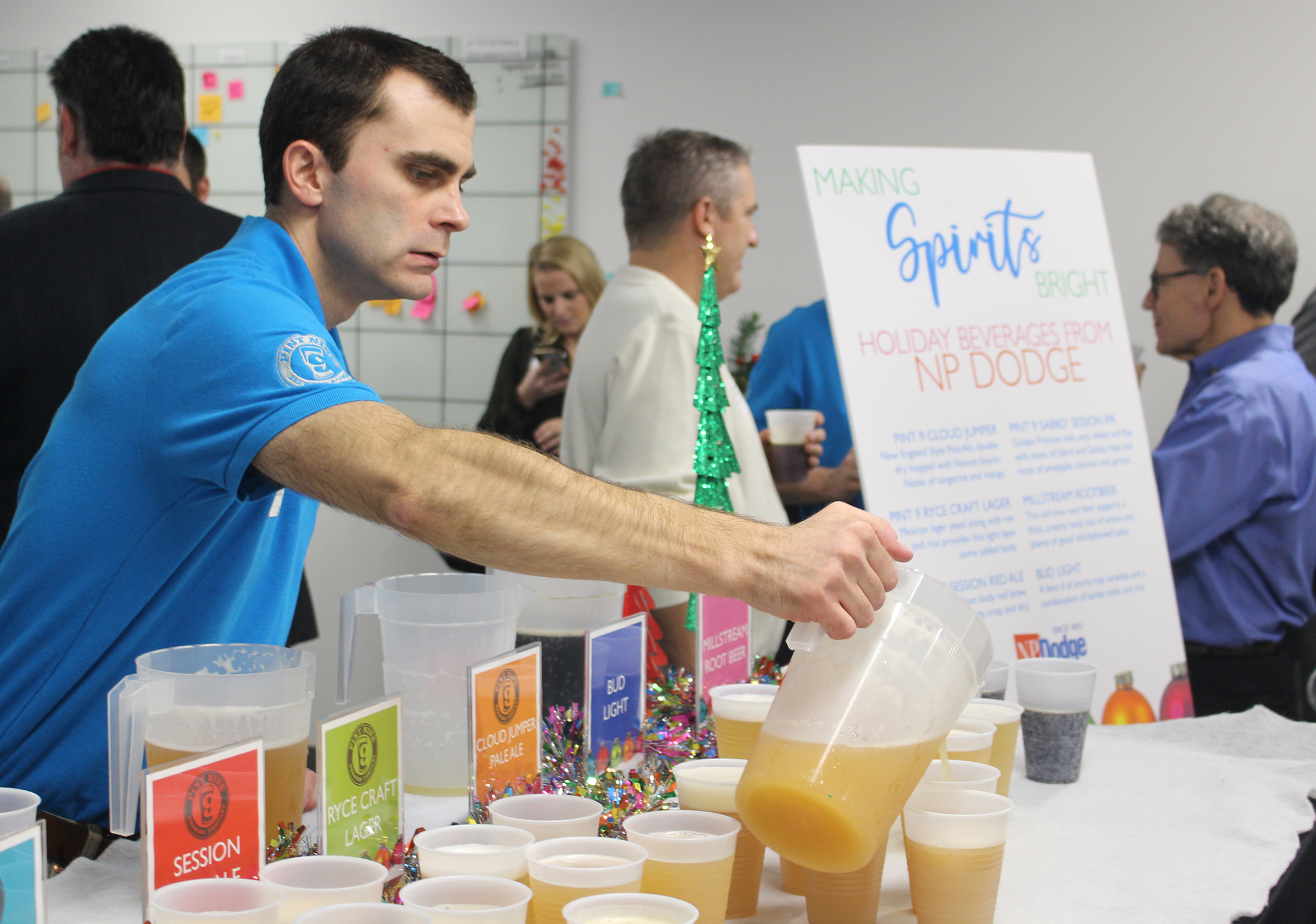 Greg Kraemer, sales associate at NP Dodge, pours drinks during the Greater Omaha Chamber Member Appreciation Holiday Open House on Thursday, Dec. 5, 2019. (Photo by Scott Stewart)