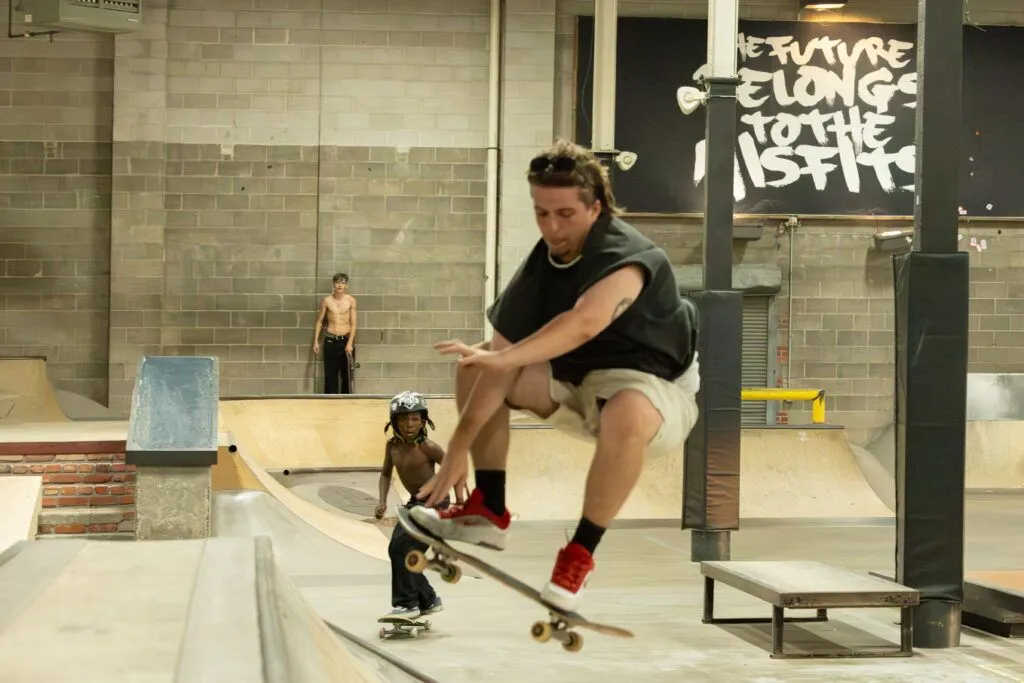 Russell makes a jump while Boogie, 10, watches from behind. “I hope they make it as far as they can … like almost up to Tony Hawk,” Boogie said.<br />(Naomi Delkamiller / Flatwater Free Press)