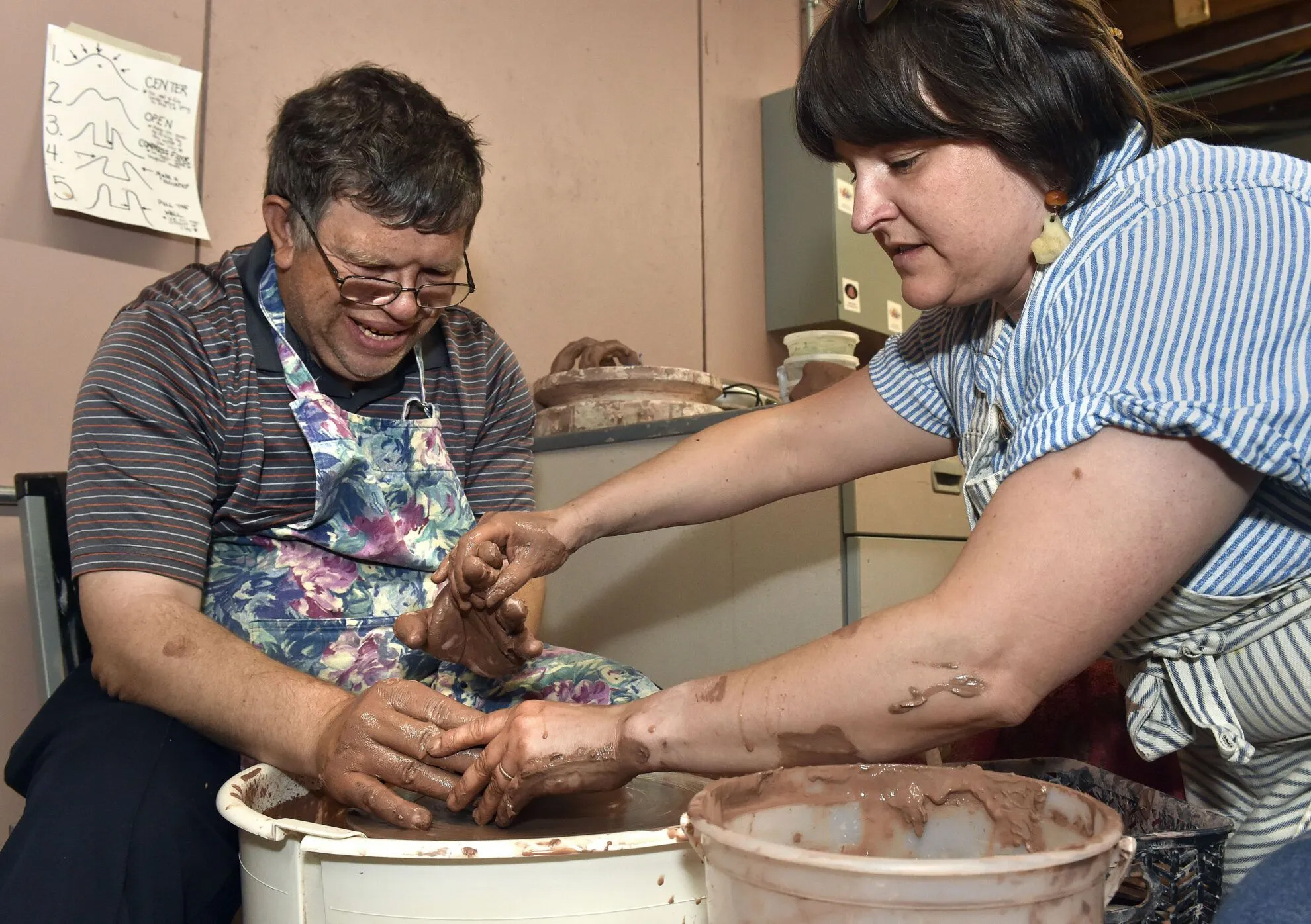 Joey Dowding gets a helping hand from studio program manager Samantha Wieland as he throws a pot at Lincoln’s Live Yes Studios on June 11, 2024. Dowding, who also plays guitar and hosts a racing podcast, said he has been coming to Live Yes since 2018.<br />(Eric Gregory / Flatwater Free Press)