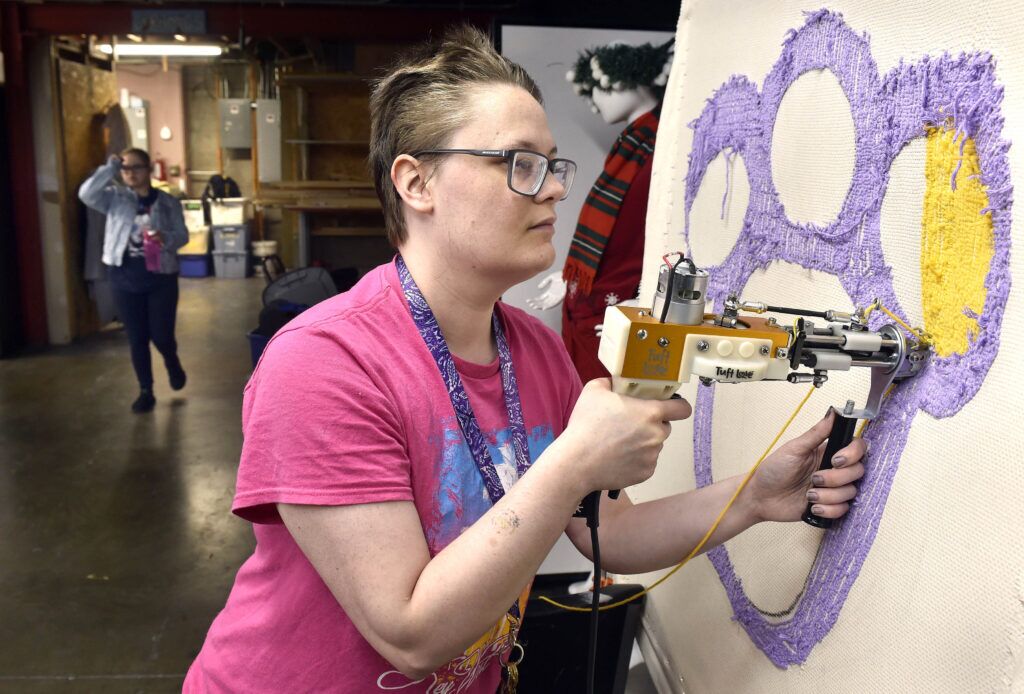 Khan Salmon uses a tufting gun to create a paw print design on June 11, 2024, at Live Yes Studios in Lincoln. Salmon, who is autistic, says that Live Yes has given him confidence, friendships and new skills.<br />(Eric Gregory / Flatwater Free Press)