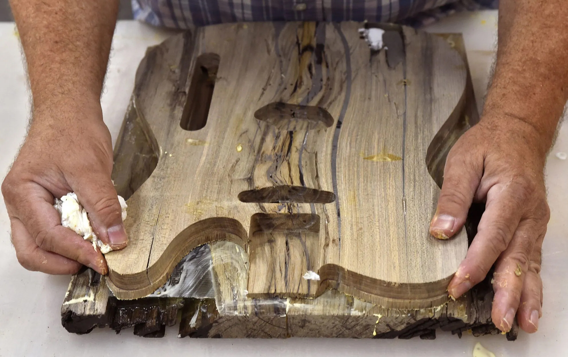 Phil Whitmarsh, the owner of Old Market Guitarworks, glues the top and bottom of a guitar body together at the Nebraska Innovation Studio in Lincoln on July 8, 2024. Whitmarsh has carved out a small business making quality guitars out of old reclaimed wood. The guitar pictured is made from century-old maple sinker wood recovered near Two Rivers, Wisconsin.<br />(Eric Gregory / Flatwater Free Press)