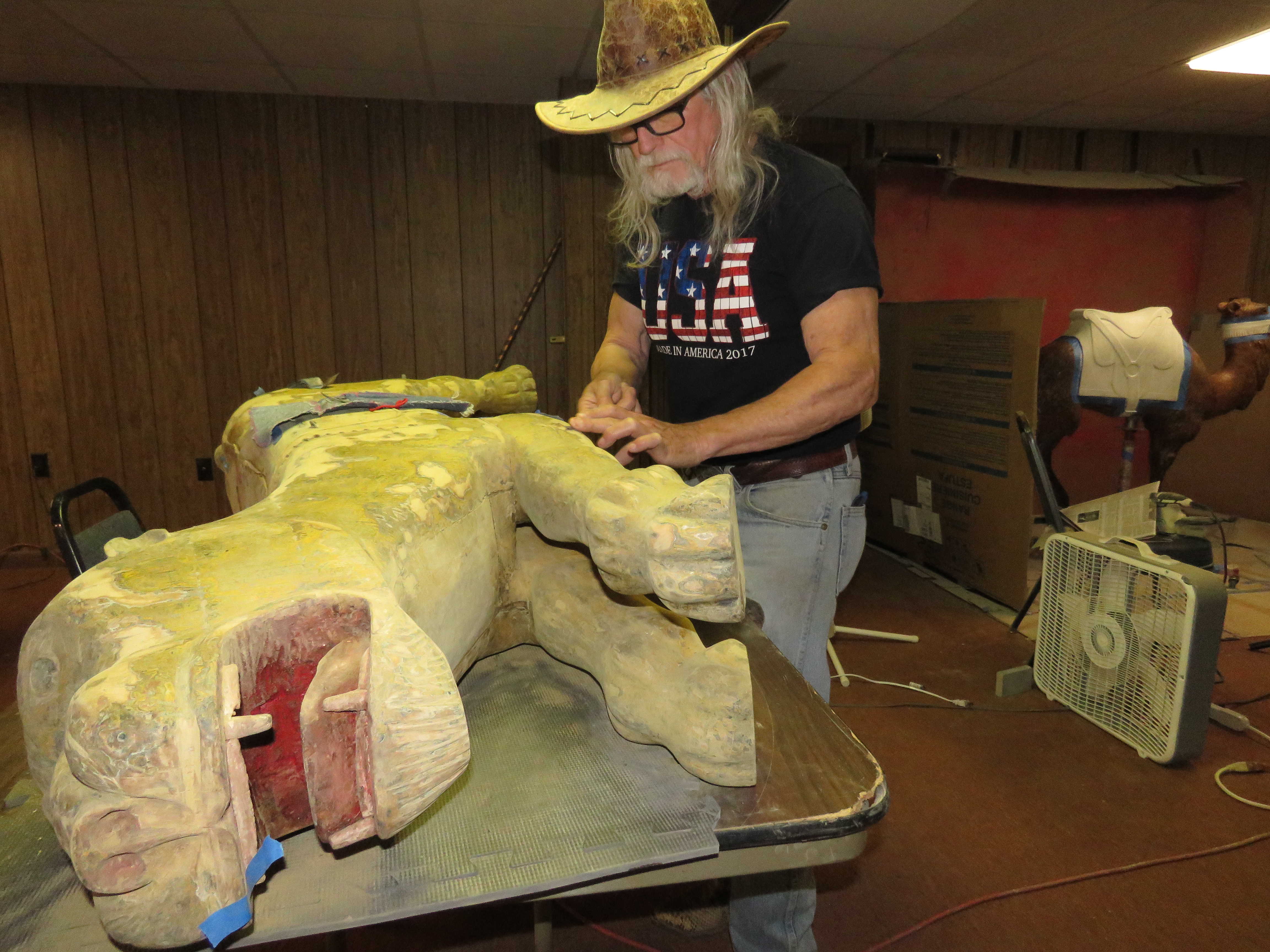 Brad Roberts of Heartwell, one of six volunteers restoring Pioneer Village carousel figures made in the 1800s to early 1900s, worked on repairs to Elsa the lion, made in 1885.<br />(Lori Potter / Flatwater Free Press)