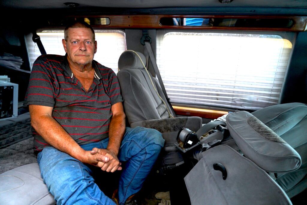 Paul Duis poses for a photo inside his GMC van on Sept. 9, 2024. Duis takes multiple medications to manage his congestive heart failure. He’s working with HEAL Omaha, a group that provides street medicine to Omaha’s unsheltered homeless population, to get medication and other health care needs. The help makes Duis a little more optimistic that he can tackle finding housing.<br />(Chris Bowling / Flatwater Free Press)