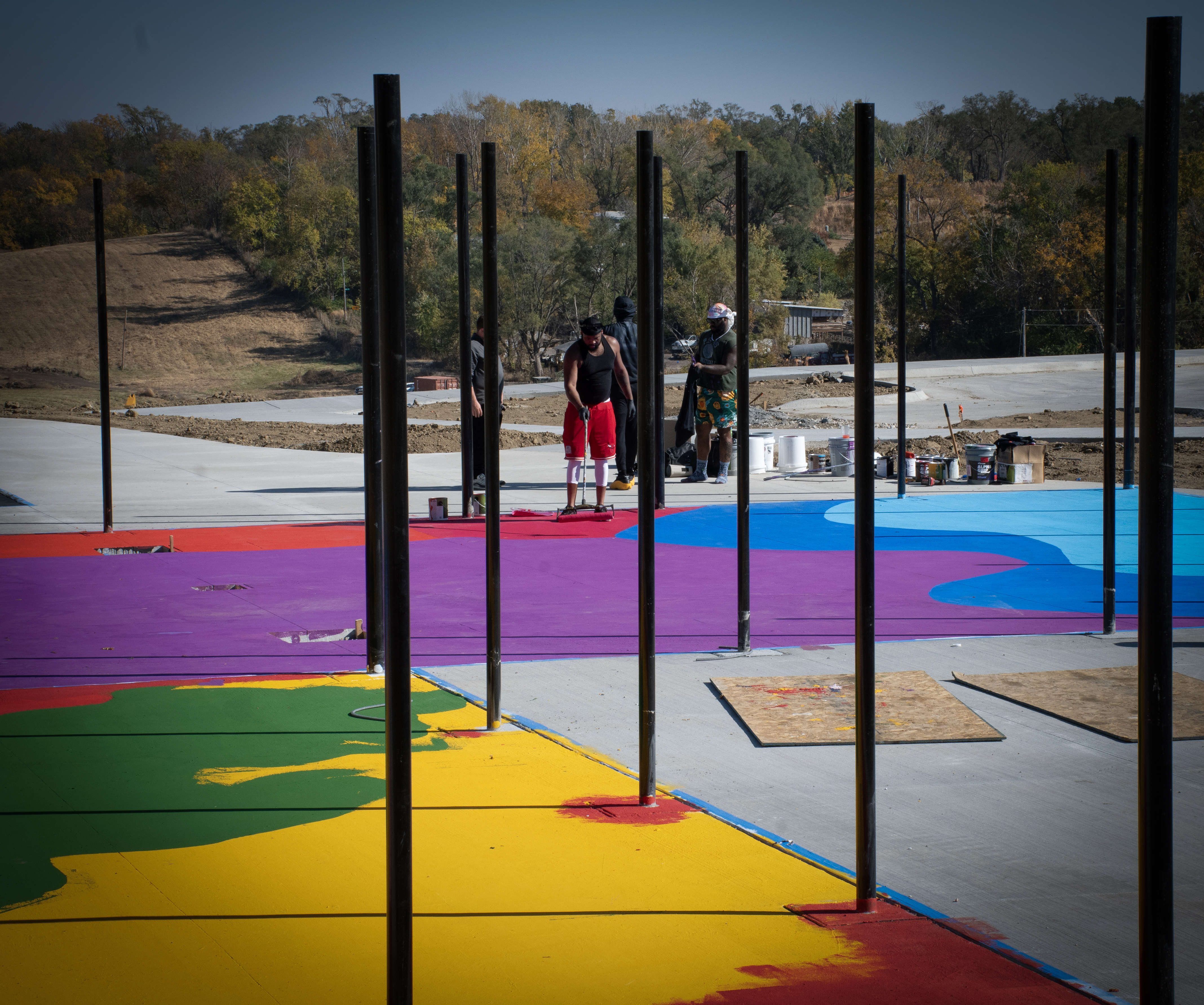 The grounds of outdoor athletic courts at Myott Park in the Bluestem Prairie residential area, which is being developed by Habitat for Humanity Omaha, are transformed into art by Frankie Zombie, a national artist who is videotaping his Omaha experience for a pilot he is developing. He currently is a co-star of the “Artfully Designed” show that is streaming on HBO. Also shown painting is crew member Dante Page.<br />(Courtesy of John Melingagio and Habitat for Humanity)