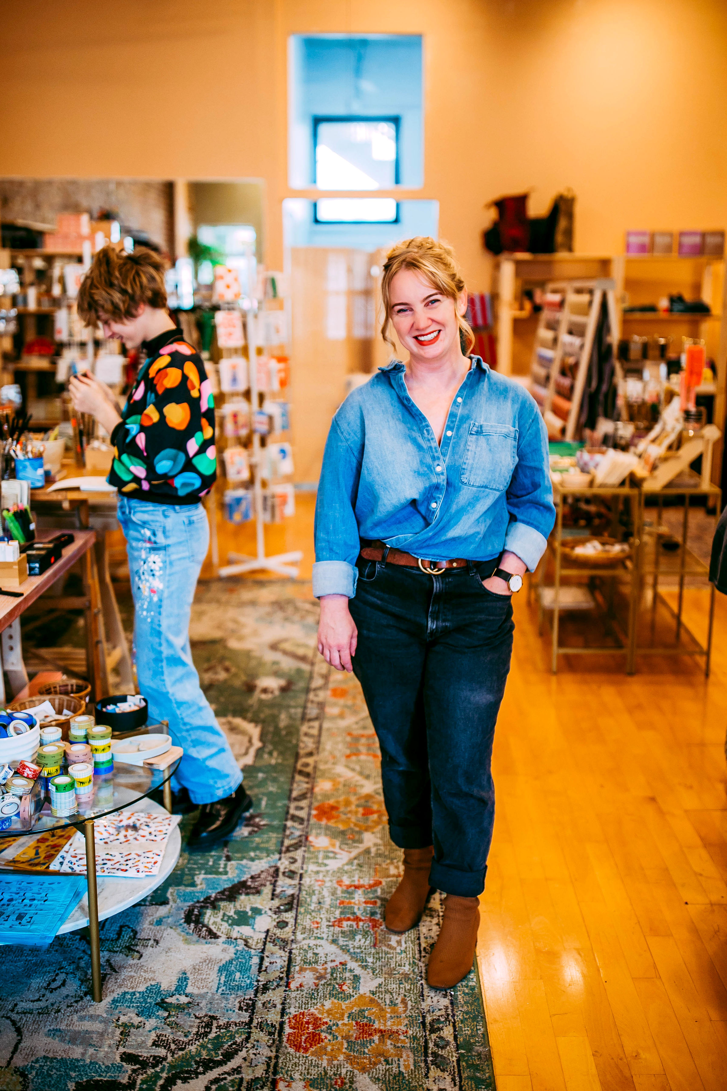 State Sen. Megan Hunt poses for a photo while her son, Ash smiles in the background. (Ariel Panowicz)