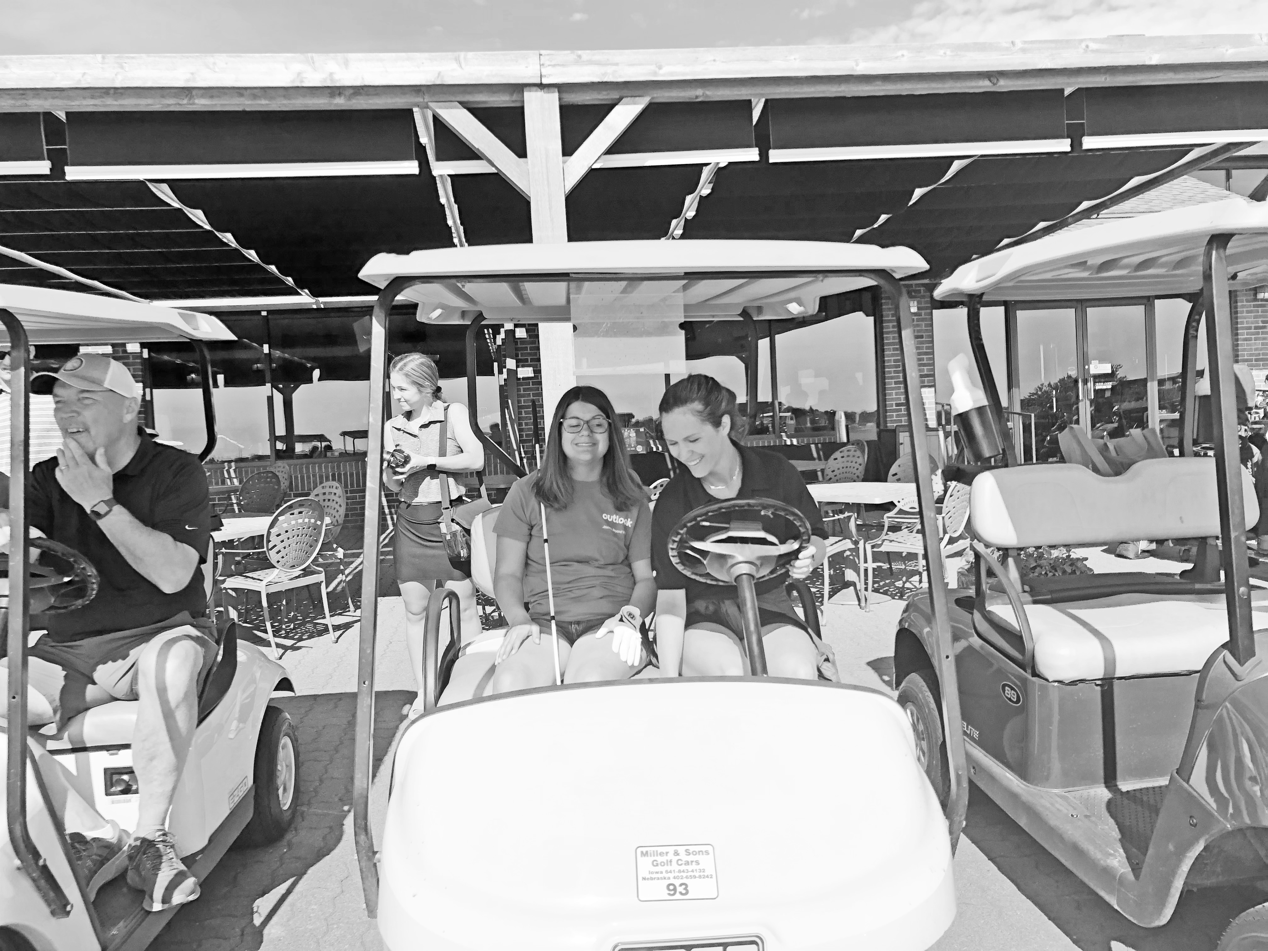 A  young lady with a white cane and her golf guide in a golf cart. (Megan Mackie)