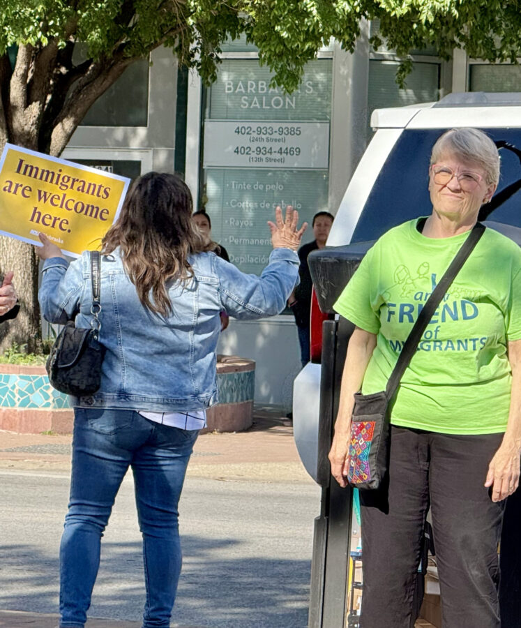 Rallygoers wave at passing cars that honk and give thumbs up to the “Stand in Solidarity” event Thursday afternoon in South Omaha.<br />(Cindy Gonzalez / Nebraska Examiner)