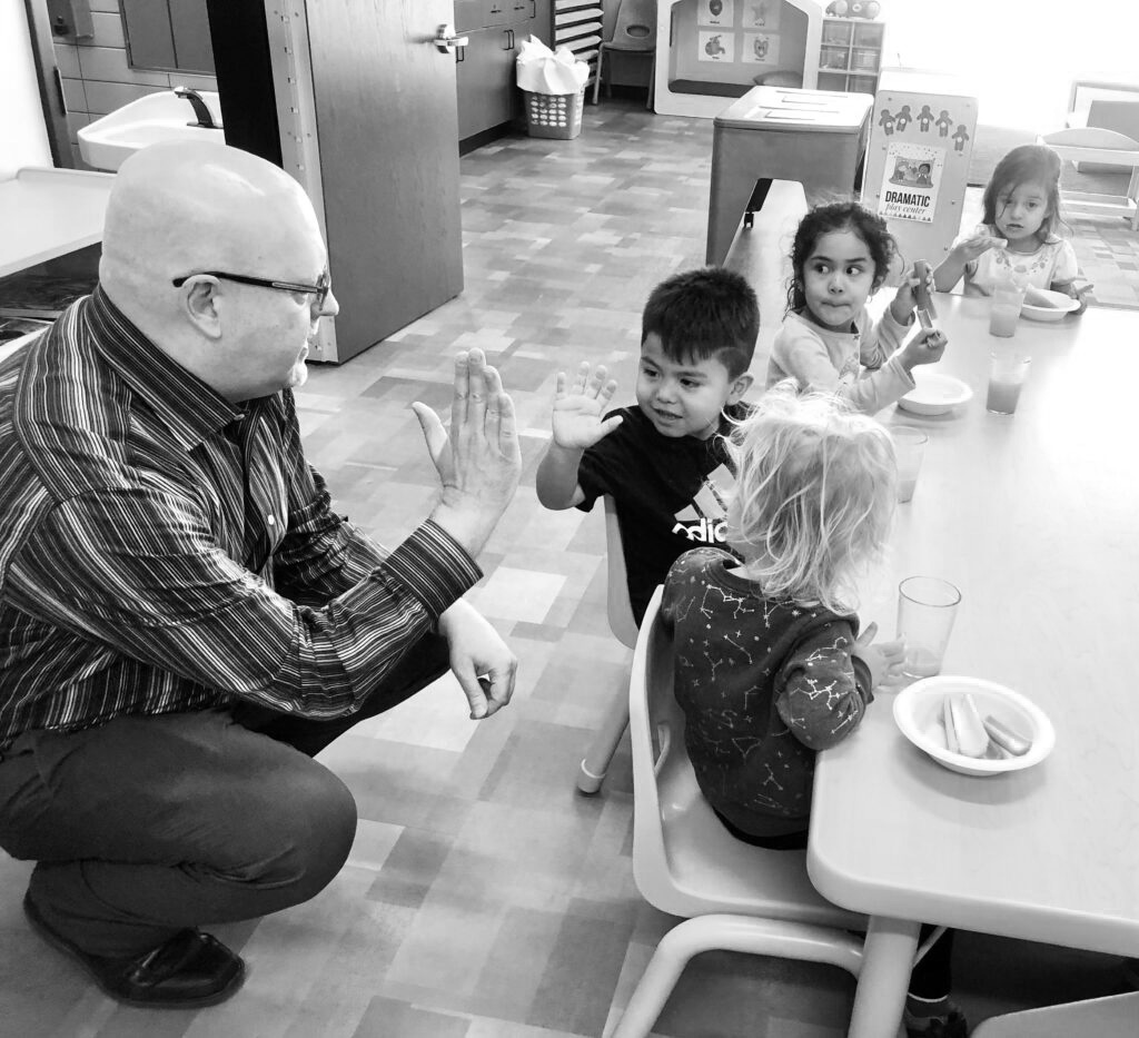 Robert Patterson, who has spent 25 years with the Kids Can nonprofit, shares some time with preschoolers at the new center. (Cindy Gonzalez / Nebraska Examiner)