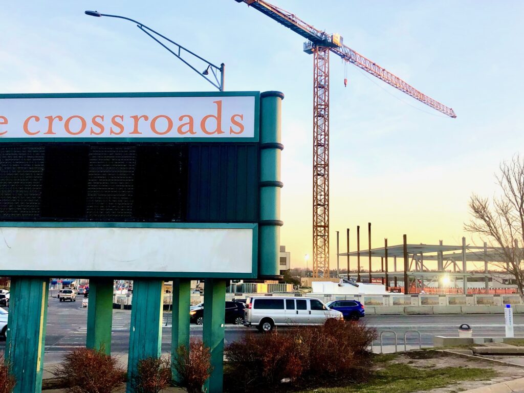 The Crossroads shopping center’s familiar sign shown here at the corner of 72nd and Dodge Streets, a high-profile intersection in Omaha that is undergoing huge changes. This view is looking south, toward the central library facility under construction. The Crossroads redevelopment team is requesting revisions that include an increase in the public tax incentive called tax-increment financing.<br />(Cindy Gonzalez / Nebraska Examiner)