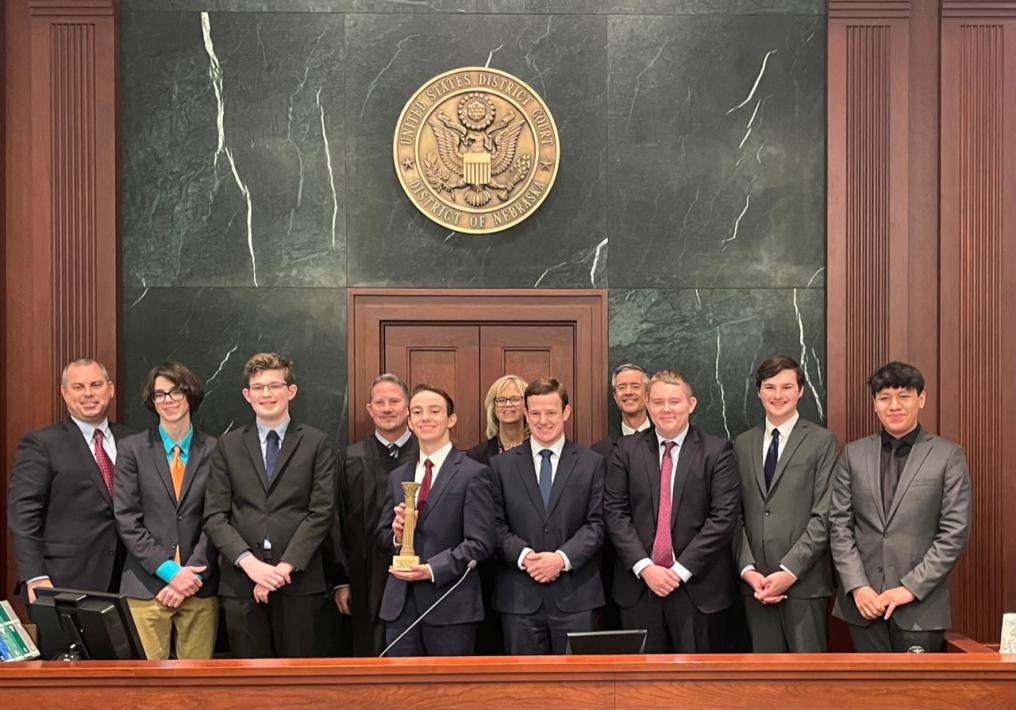 Creighton Prep students standing with their coaches and Justice Funke and Judge Bazis following the championship round of the state competition against Duchesne Academy. This year’s team secured a win at the Federal Courthouse in Omaha, Neb. on December 5-6, 2022. (Courtesy of Nebraska State Bar Foundation)