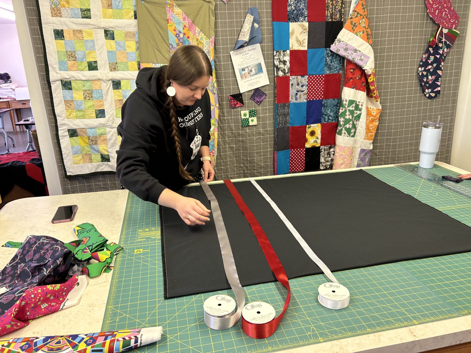Jessi Bean strings ribbons on a “ribbon skirt” she is working on at the Whiteclay Makerspace.<br />(Paul Hammel / Nebraska Examiner)