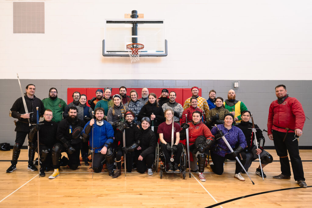 Members of the Nebraska Swordfighters Guild, along with members of the Omaha Kunst des Fechtens and Rocky Mountain Swordplay guilds, pose in the gymnasium at Lincoln’s Air Park Community Center on Saturday, Jan. 25, 2025.<br />(Liz McCue / Flatwater Free Press)