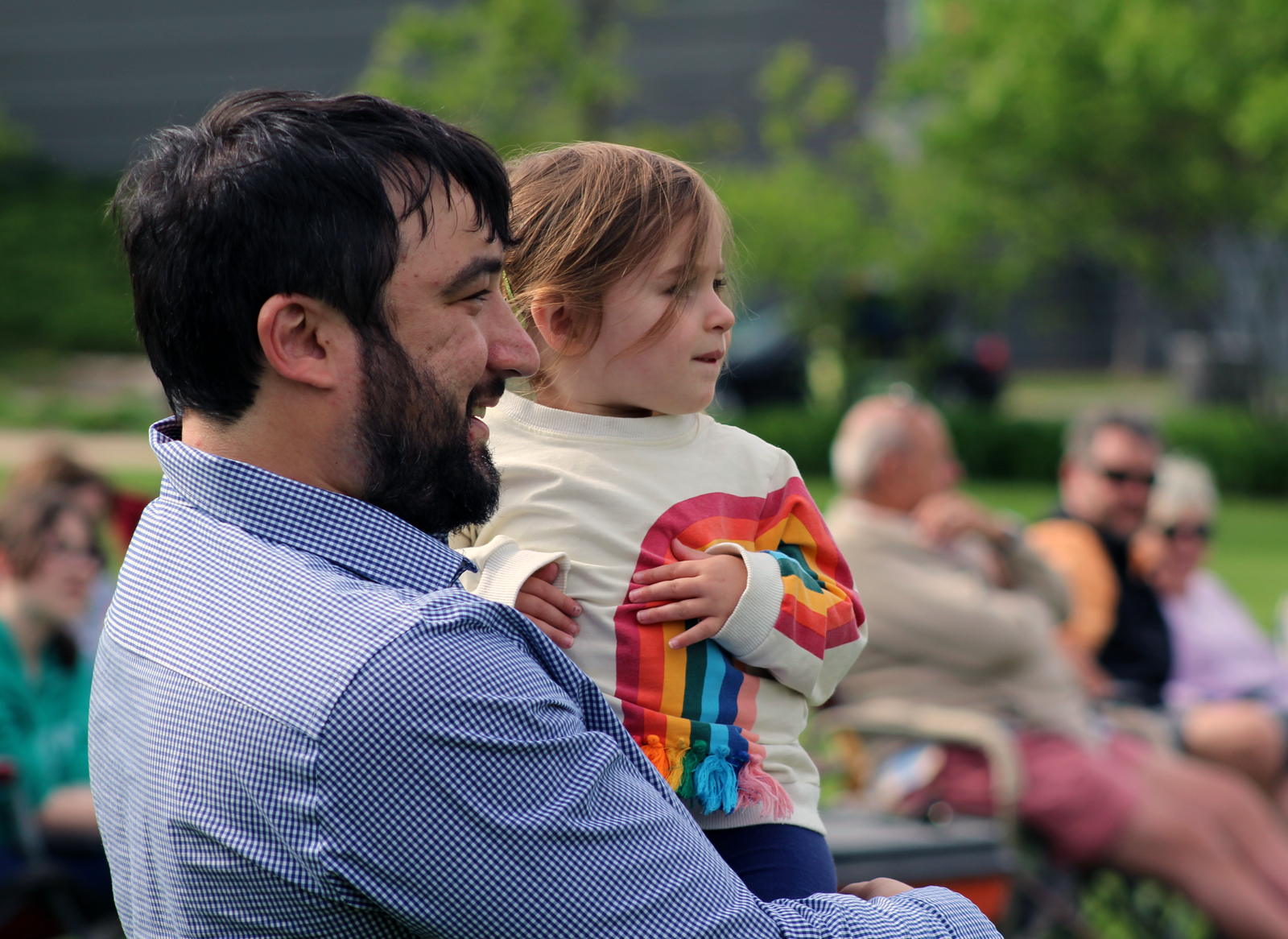 David Martin and 22-month-old Yvette watch musicians perform at Turner Park in Midtown Crossing during Legal Aid of Nebraska’s Omaha Gives celebration on Wednesday, May 23, 2019. (Photo by Scott Stewart)