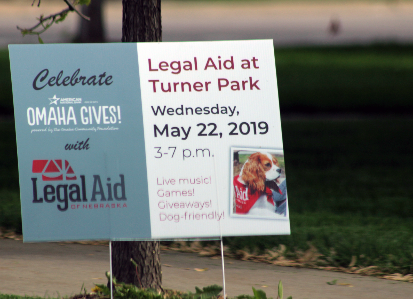 A sign directs passers-by to enjoy live music, games and fun at Turner Park during Park in Midtown Crossing during Legal Aid of Nebraska’s Omaha Gives celebration on Wednesday, May 23, 2019. (Photo by Scott Stewart)