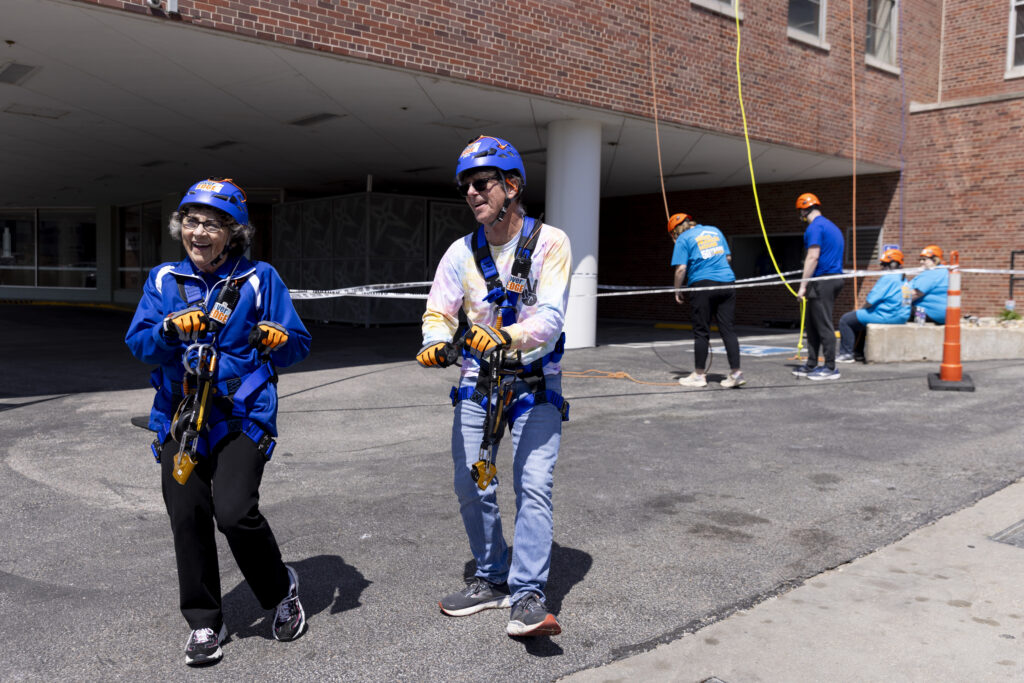 Sister Stephanie Matcha and reporter Chris Burbach dance together after both rappelled down the side of The Highline Apartments in downtown Omaha on May 3, 2025. Matcha “always brings that joy and energy,” Siena Francis CEO Linda Twomey said.<br />(Anna Reed / Flatwater Free Press)