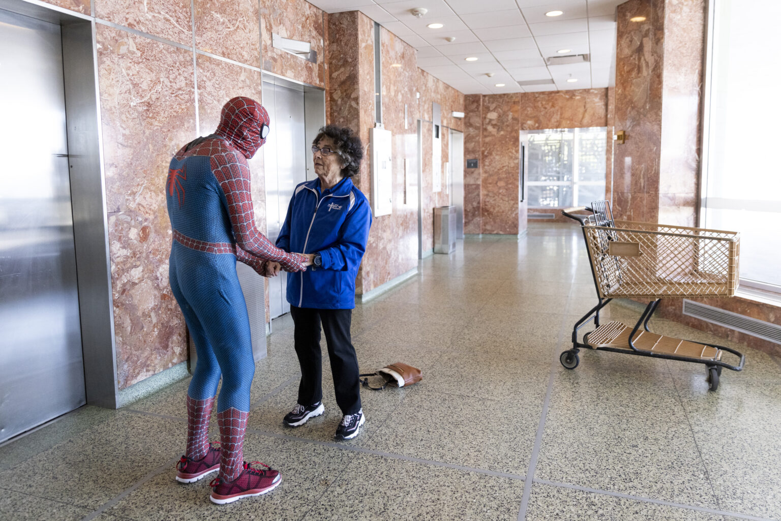 Dave Kuiper, dressed as Spider-Man, comes in for a hug with Sister Stephanie Matcha before she rappelled down the side of The Highline Apartments in downtown Omaha on May 3. For 50 years, Matcha has volunteered and worked at Siena Francis House, where Kuiper was once a guest and is now the dock and logistics manager.<br />(Anna Reed / Flatwater Free Press)