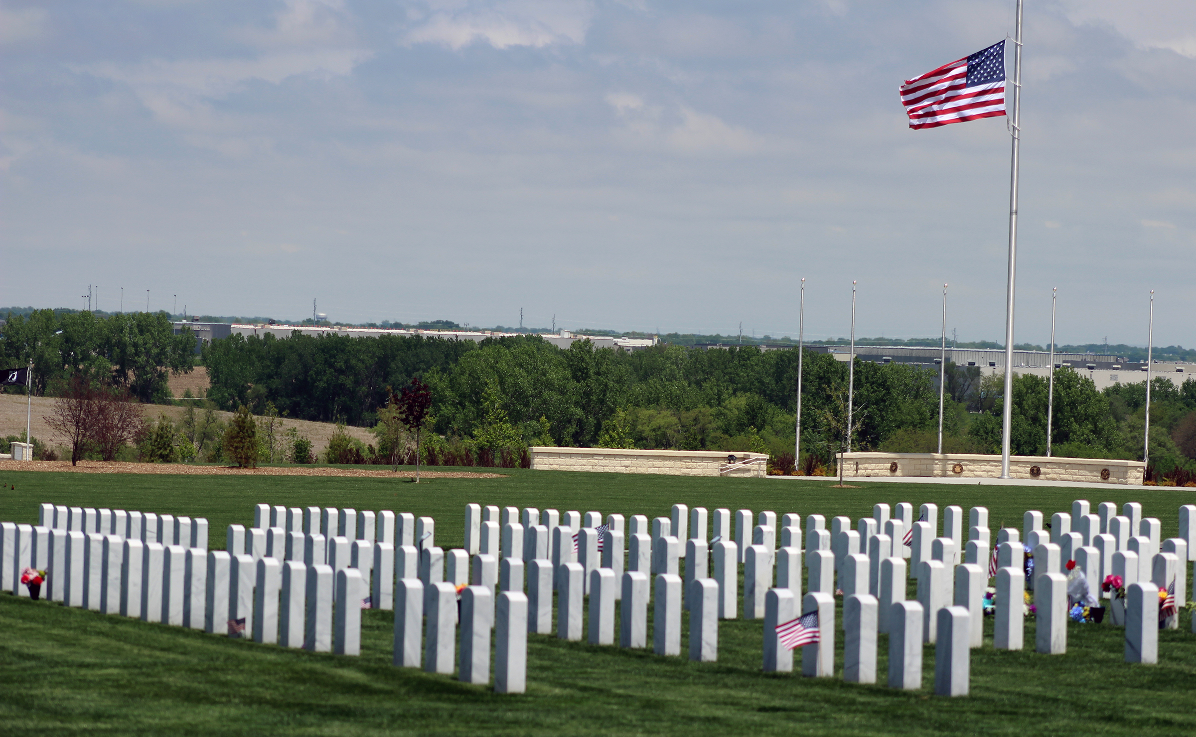 A flag waves over rows of graves at the Omaha National Cemetery outside Papillion on Wednesday, May 20, 2020. (Photo by Scott Stewart)