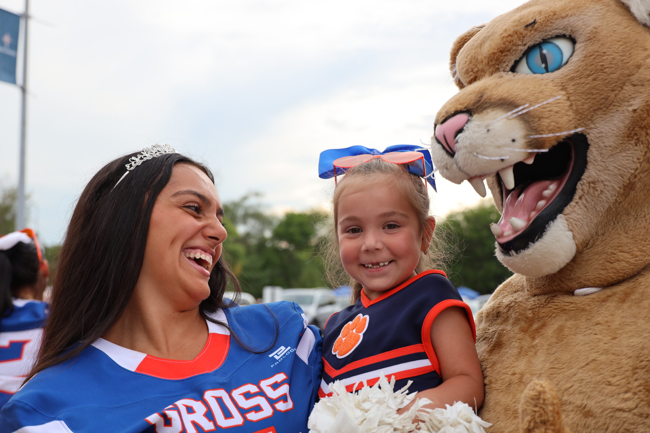 Katya Kohut beams while being held by one of the Gross Catholic cheerleaders, Gabby Hunter and mascot Freddie Cougar, at the school’s homecoming pep rally.<br />(Susan Szalewski / The Catholic Voice)