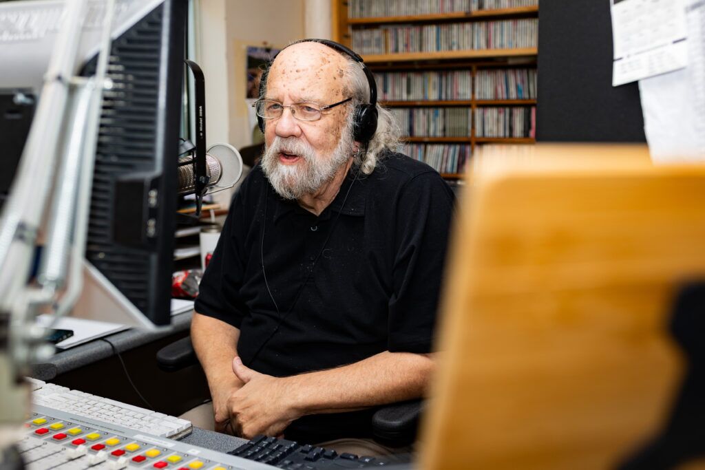 Radio personality Otis Twelve speaks to a listener on air at KVNO’s studio in Omaha on Sept. 27, 2024. Twelve, whose real name is Douglas Wesselmann, retired from the station on Oct. 4 after 18 years.<br />(Joseph Saaid / Flatwater Free Press)