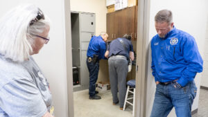 Marion County Record reporter Phyllis Zorn and Sheriff Jeff Soyez stand outside the evidence room where an undersheriff signs over newspaper property to a forensic expert.<br />(Kansas Reflector / Sherman Smith)