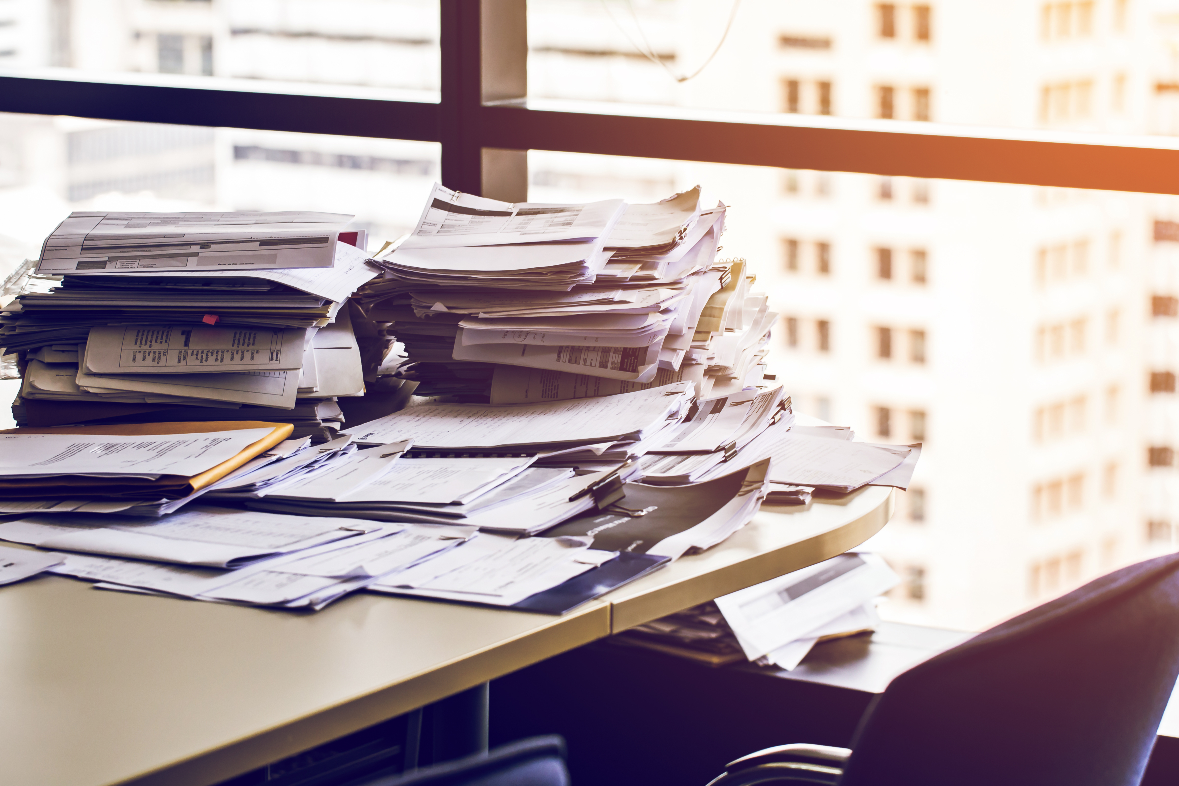 Messy piles of paper sit on a desk. Each year, thousands of people are sued and don’t participate in their lawsuit. For some, this is because they were never notified, or the documents they received were difficult to understand.<br />(Shutterstock)