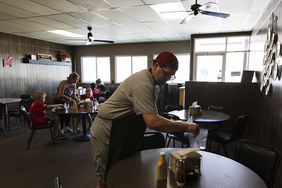 Owner Adam Witchell clears a table during the lunch hour at the City Cafe. (Ryan Soderlin / Flatwater Free Press