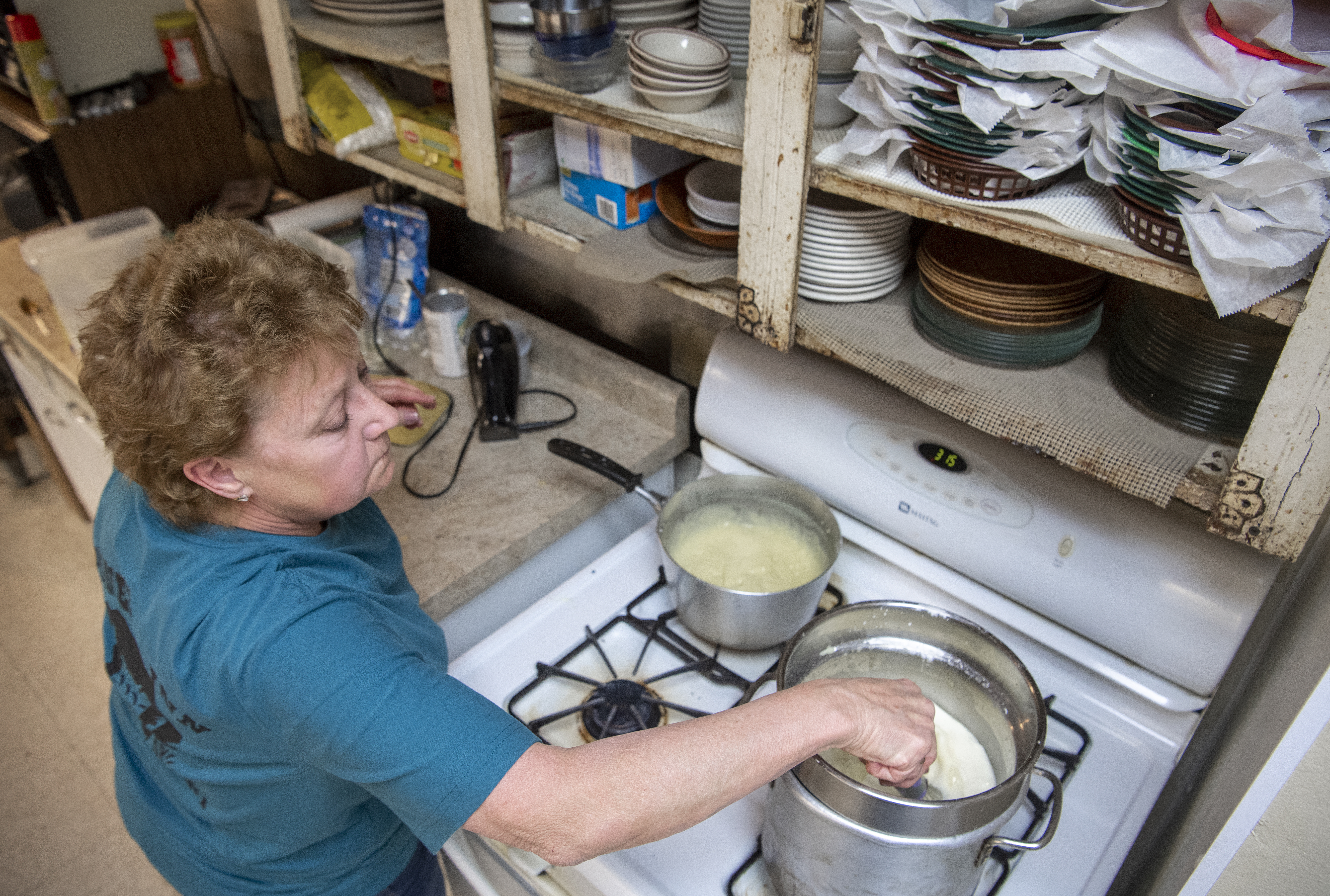 Mary Flagle prepares the ingredients for coconut cream pies on the stove Friday, March 20, 2020, at the Pioneers Inn restaurant in Gilead. (Francis Gardler/Lincoln Journal Star via AP)