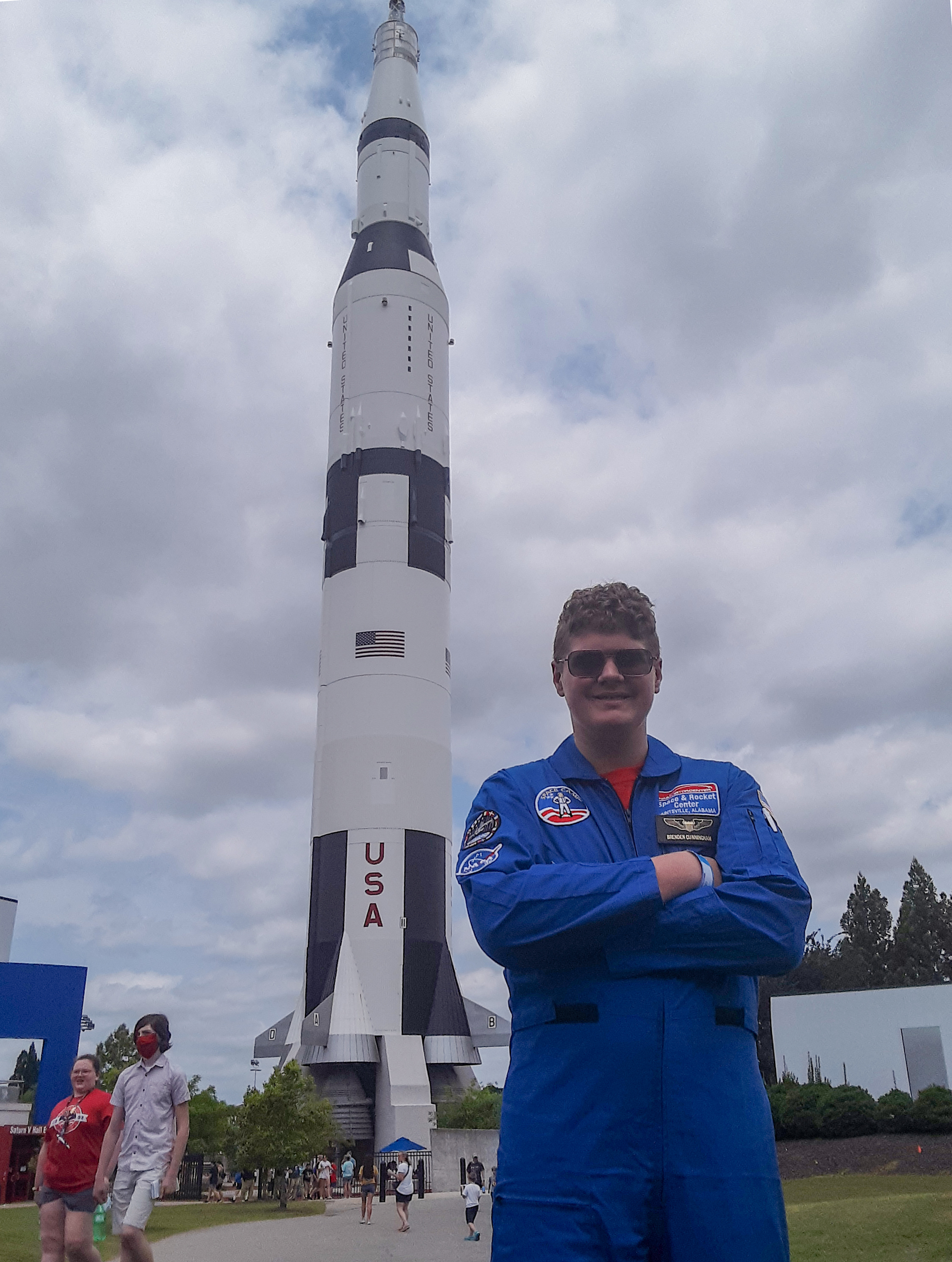 Brenden Cunningham stands by a Saturn V rocket. (Amy Cunningham via RPS)
