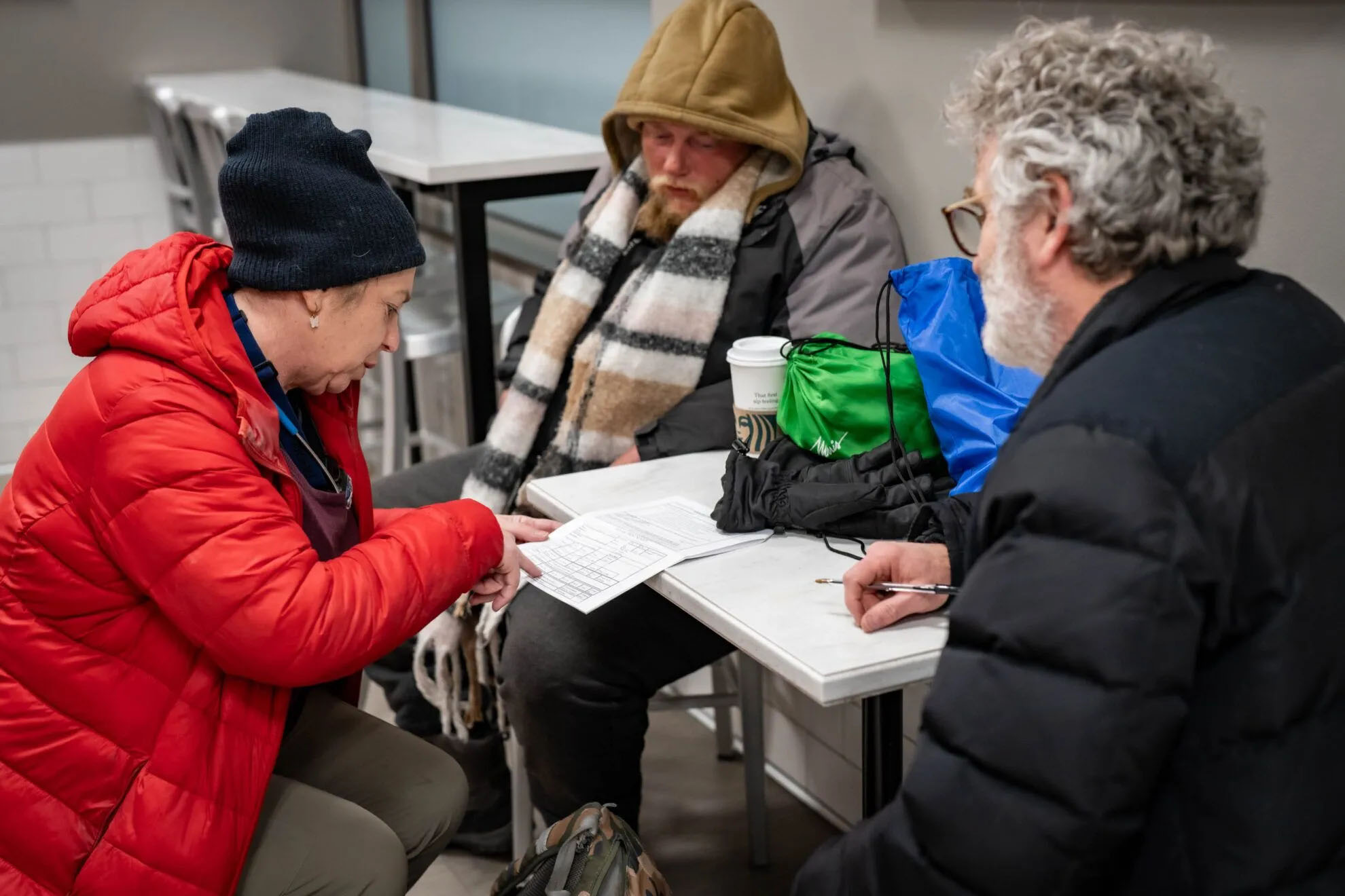 Melissa Neuenfeldt (left) and Todd Fleischer (right) examine a questionnaire for Omaha’s homeless population including Jonathan Martin (center) during the annual Point-in-Time Count. The nationwide survey provides data about the United States’ homeless population.<br />(Abioloa Kosoko / Flatwater Free Press)