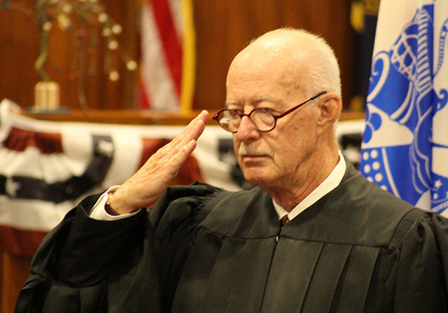 Judge James T. Gleason salutes the four most recent graduates of the Douglas County Veterans Treatment Court at a graduation ceremony July 24, 2019, in the legislative chambers of the Omaha-Douglas Civic Center. (Photo by Scott Stewart)