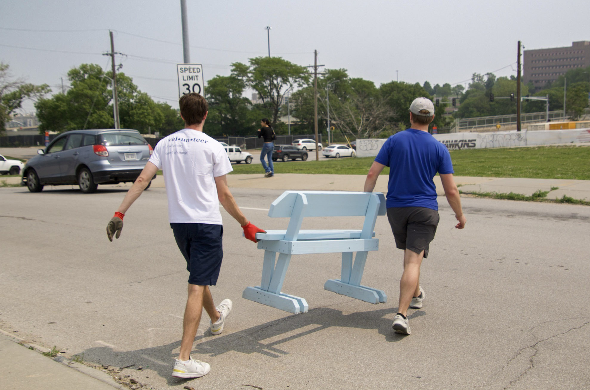 Jack Cicin (left) and Noah Mahlberg carry a homemade wooden bench to a bus stop in midtown Omaha in June. Their group, Strong Towns, aims to improve access to public transit.<br />(Jeremy Turley / Flatwater Free Press)