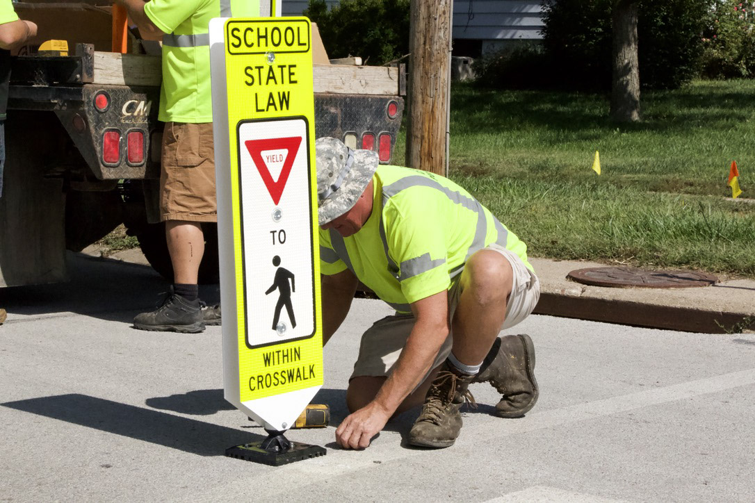 A Blair city employee installs a vertical yield sign at a crosswalk near Blair’s Arbor Park Elementary School after city officials approved a pedestrian safety pilot program.<br />(Jeremy Turley / Flatwater Free Press)