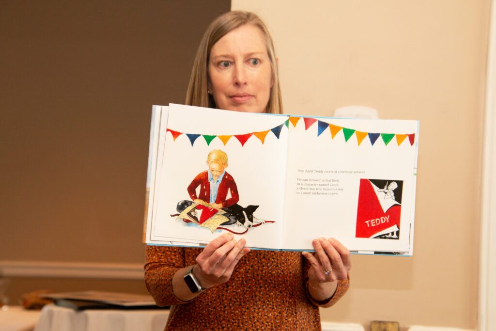 Carla Ketner of Seward holds up a page from her debut children’s book, “Ted Kooser: More than a Local Wonder.” Ketner and illustrator Paula Wallace presented the book at an October meeting of Omaha’s Eclectic Book Review Club.<br />(Jeremy Turley / Flatwater Free Press)