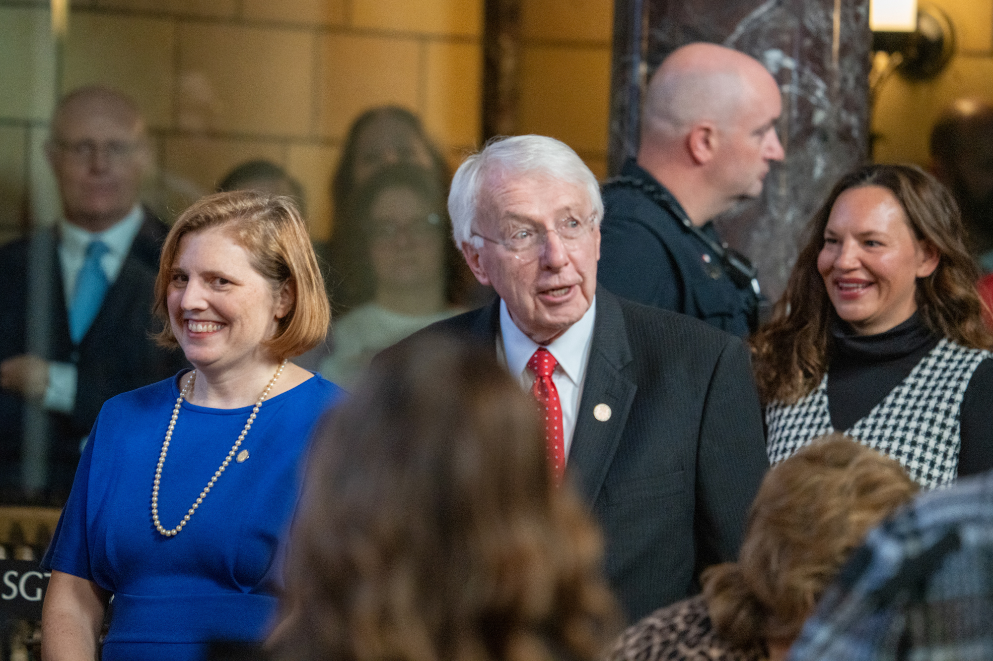 State Sens. Machaela Cavanaugh (left) of Omaha, Merv Riepe (center) of Ralston and Danielle Conrad of Lincoln join at the back of the legislative chamber to escort the chief justice of the Nebraska Supreme Court on the first day of the 2025 legislative session on Jan. 8, 2025.<br /> (Zach Wendling / Nebraska Examiner)