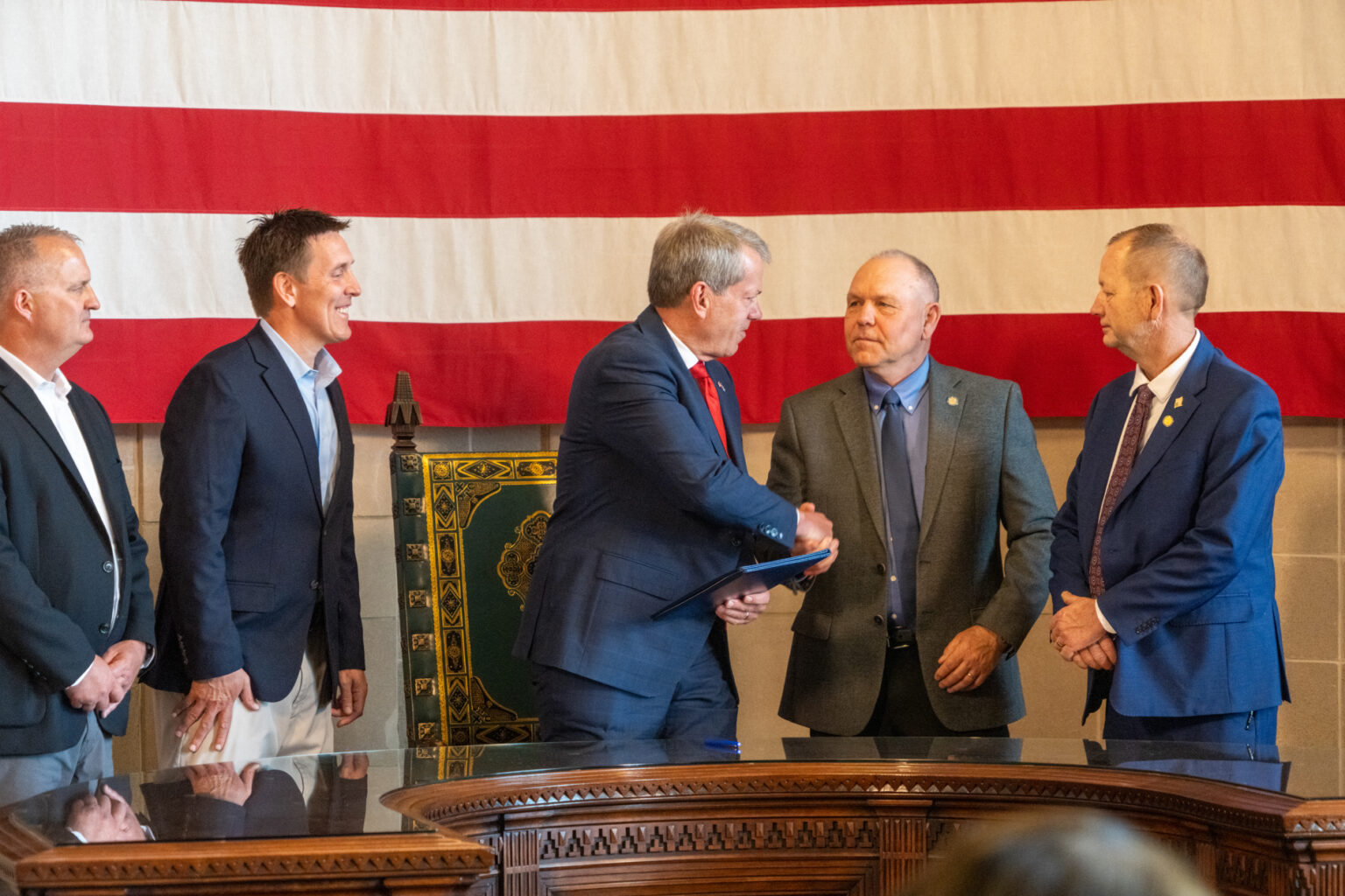 Nebraska Gov. Jim Pillen (center) shakes hands with State Sen. Tom Brandt of Plymouth, whom the governor worked with to merge two state agencies partly to focus more attention on the state’s water resources. To the right is State Sen. Barry DeKay of Niobrara, chair of the Legislature’s Agriculture Committee. At left are Matt Manning and Jesse Bradley, who will lead the new Nebraska Department of Water, Energy and Environment,  May 7, 2025.<br />(Zach Wendling / Nebraska Examiner)