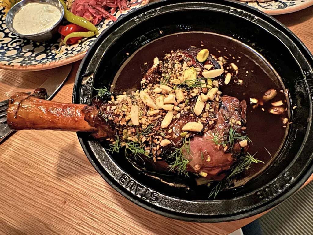 The lamb dish is served tableside in a clay tajine. The bone-in shank is served with pomegranate jus, dill and dukkah, a Middle Eastern condiment consisting of a mixture of herbs, nuts, and spices.<br /> (Sarah Baker Hansen / Flatwater Free Press)