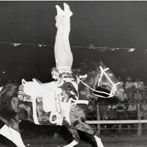 Tad Lucas stands nearly on her head while on horseback infront of an audience.<br />(Courtesy of the National Cowboy &amp; Western Heritage Museum)