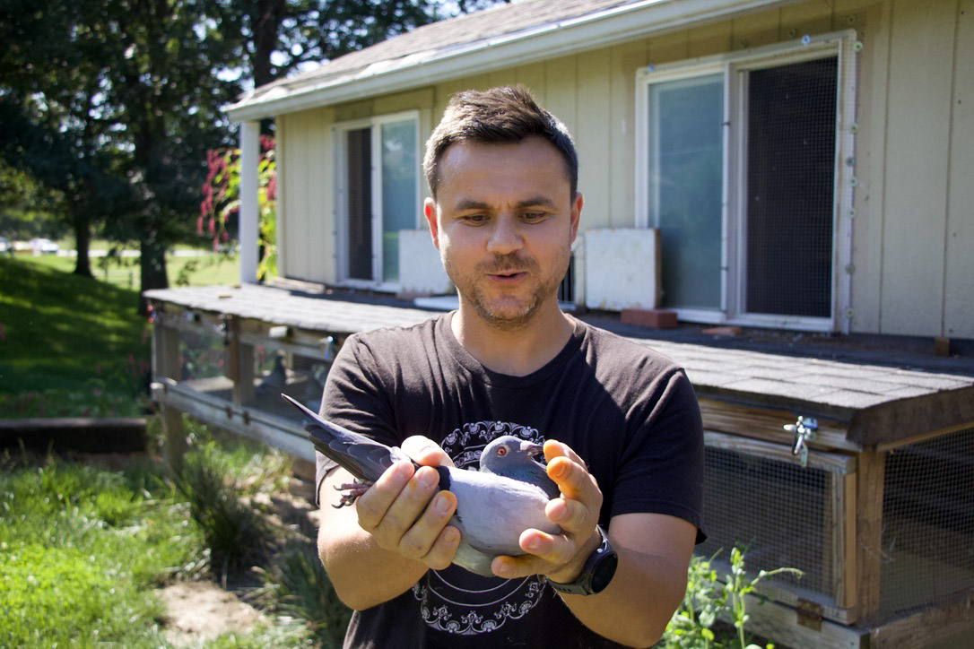 Peter Tudor, a member of the Omaha Racing Pigeon Association, handles a pigeon in front of a loft on his Omaha property.<br />(Jeremy Turley / Flatwater Free Press )
