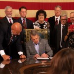 Nebraska Gov. Jim Pillen signs State Sen. Tom Brewer’s proposal to allow concealed carry of handguns without a permit or training on Tuesday, April 25, 2023. Brewer (at left) and nearly half of Nebraska’s state senators joined the signing.
(Zach Wendling / Nebraska Examiner)
