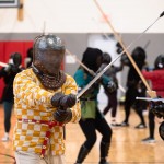 Participants at the Nebraska Swordfighters Guild’s January Fight Camp wear colorful gambesons – traditional padded or quilted jackets that would have been worn under armor in medieval combat. The gambesons, along with gloves, gorgets (steel or leather garments that protect the neck) and masks help fighters stay safe during exercises and sparring. 
(Liz McCue / Flatwater Free Press)