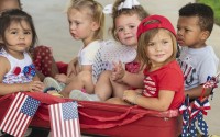 Children from Stepping Stone School in Tyler, Texas, ride together in a wagon pulled by their teacher for their annual parking lot Fourth of July parade on Friday, July 3, 2020. 
(Sarah A. Miller / Tyler Morning Telegraph via AP)
