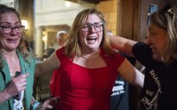 State Sen. Machaela Cavanaugh, center, hugs supporters, April 27, 2023, at the Nebraska State Capital in Lincoln, Neb. The Nebraska Legislature has long prided itself on being a paragon of collegiality and function, as the only single-chamber, nonpartisan Legislature in the country. But after a vicious 2023 session in which the body of 49 lawmakers remained irreconcilably split, Nebraska’s statehouse is beginning to reflect broad, national discord. (Larry Robinson / Lincoln Journal Star via AP)