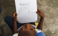 Jadlenzky Louis holds a drawing made by his mother Guirlaine Reveil that shows a man holding a gun as she approaches a police station, a real-life scenario that occurred a couple of years ago, during a class for adults to learn how to help their children overcome trauma and fear amid violence, in Port-au-Prince, Haiti, Sunday, May 5, 2024.  
(Ramon Espinosa / AP Photo)